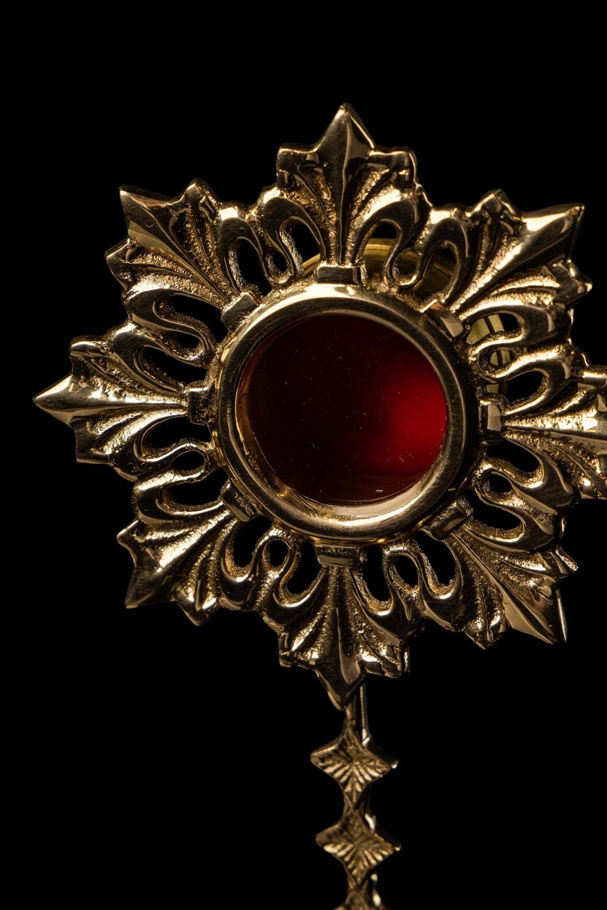 Brass reliquary upper close-up showing red center and ornate raised sunburst
