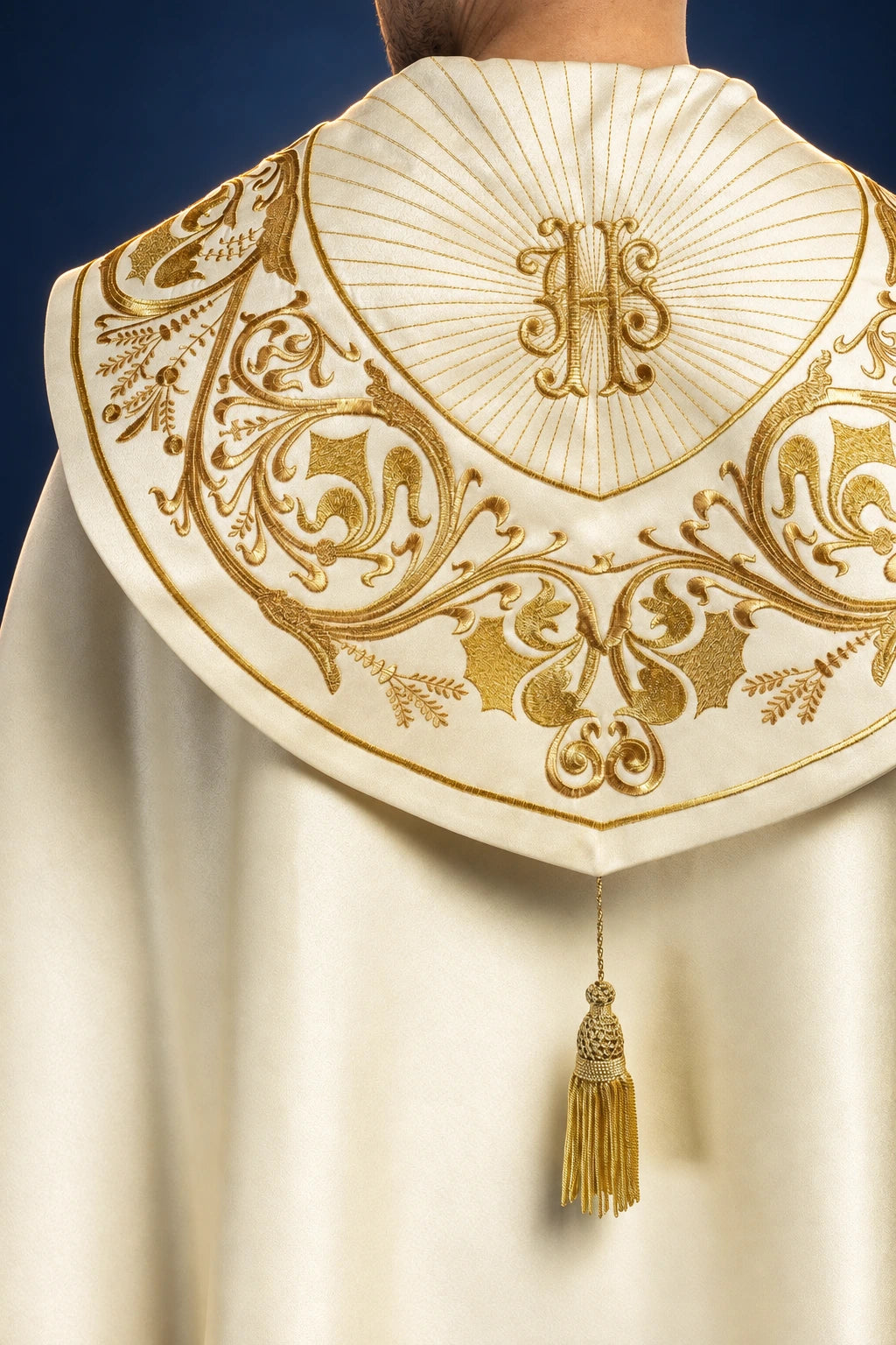 Rear view of the cope’s hood with gold IHS embroidery, scrolling floral motifs, and a dangling tassel clasp