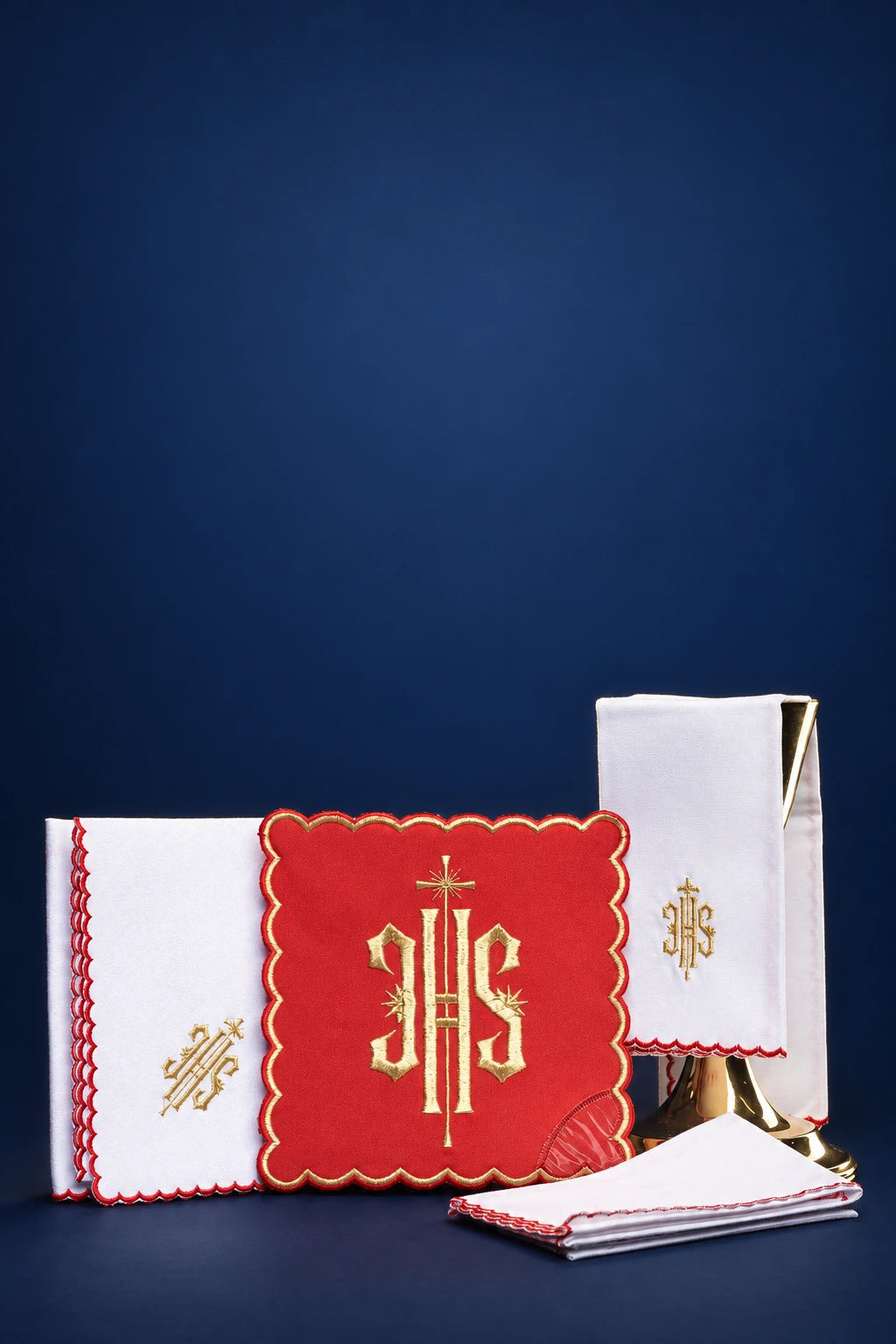 Red altar linen set with embroidered IHS motif and gold cross details, shown folded