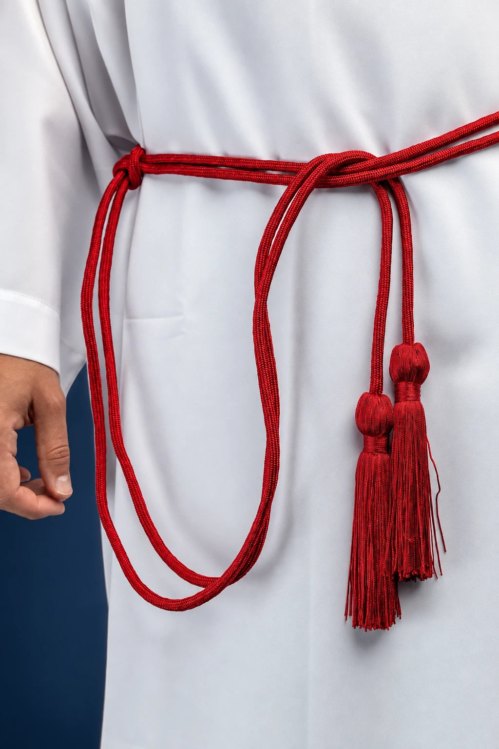 Red liturgical cincture tied at the waist, with long hanging decorative tassels