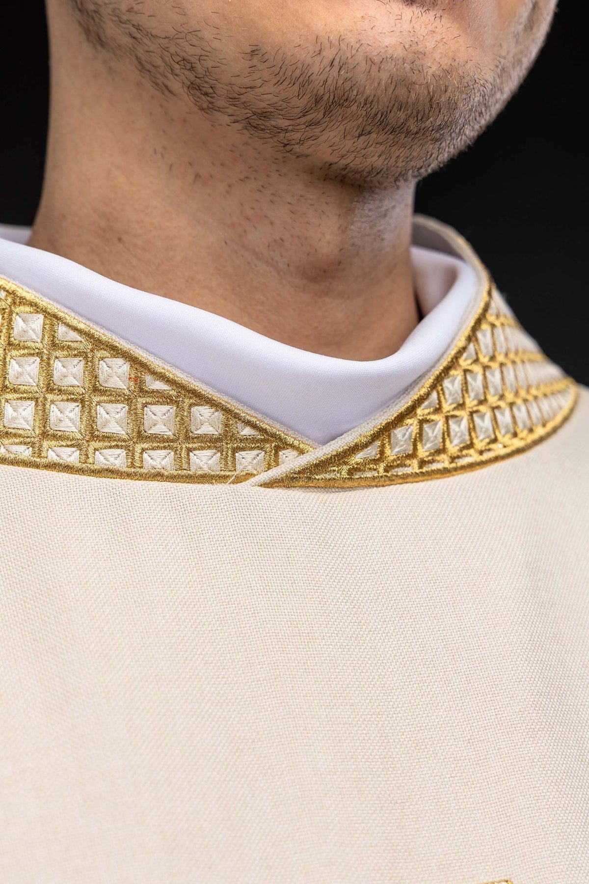 Ecru dalmatic close-up showing the white collar and gold embroidery