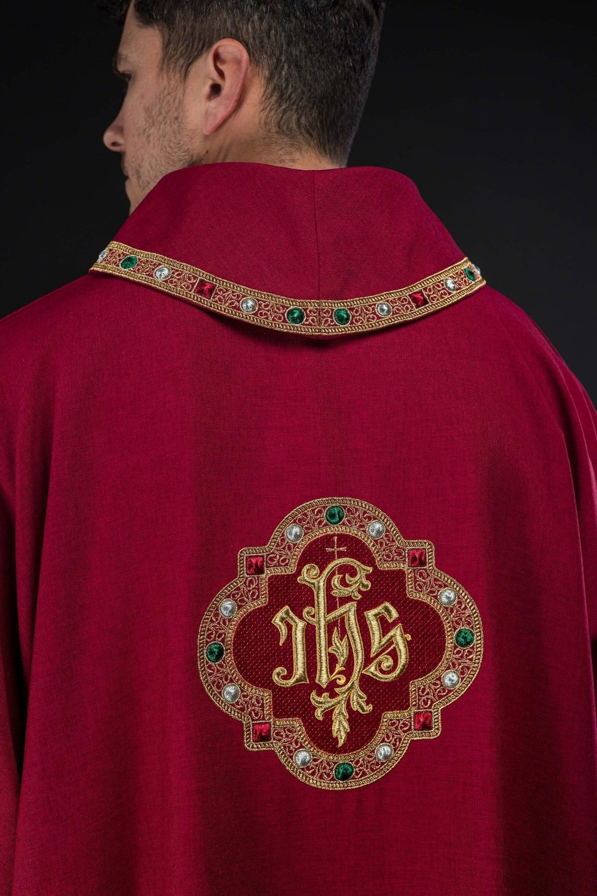 Red dalmatic back worn view with embroidered IHS symbol and decorative collar trim