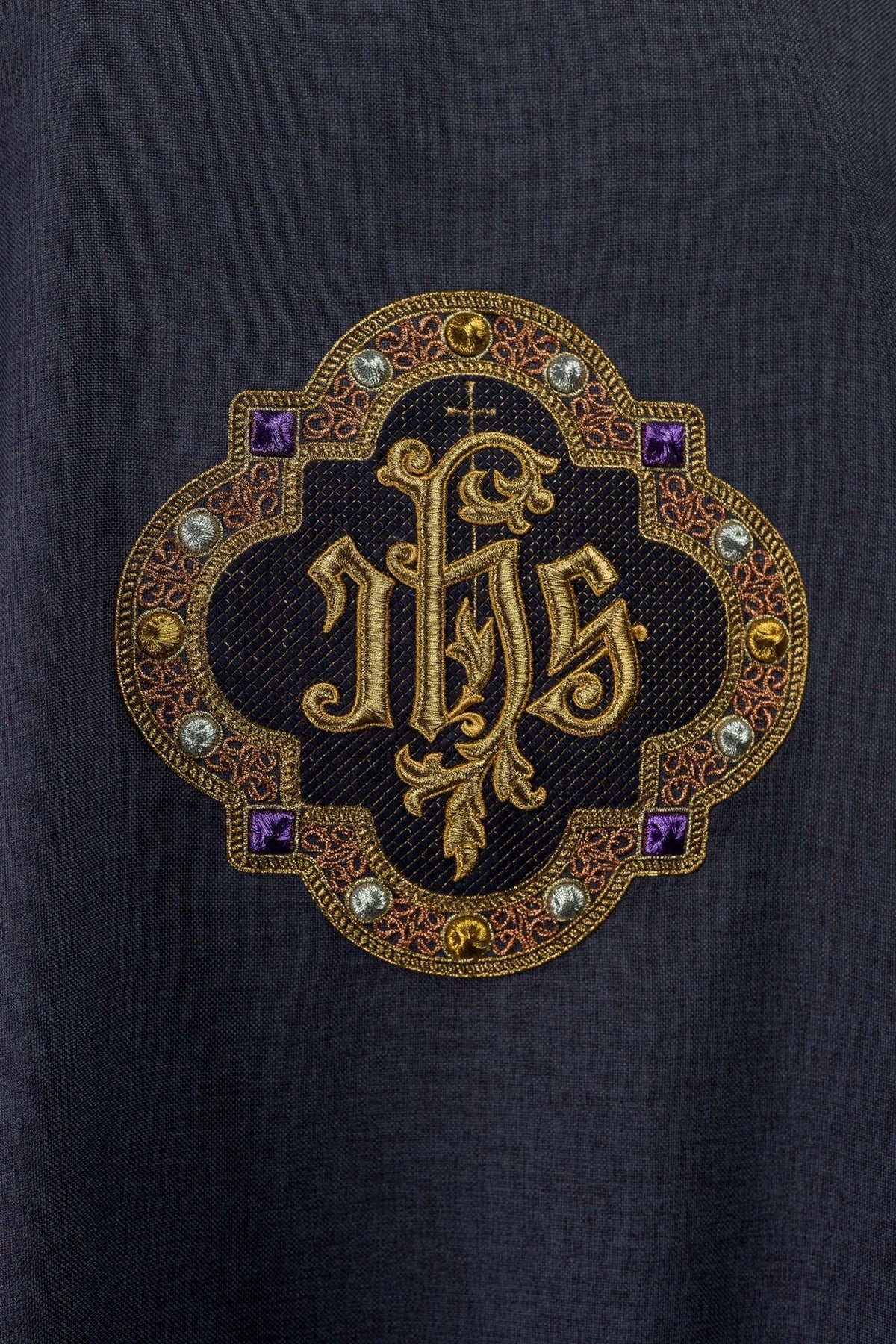 Close-up of dalmatic embroidered IHS symbol with ornate gold, purple and silver details