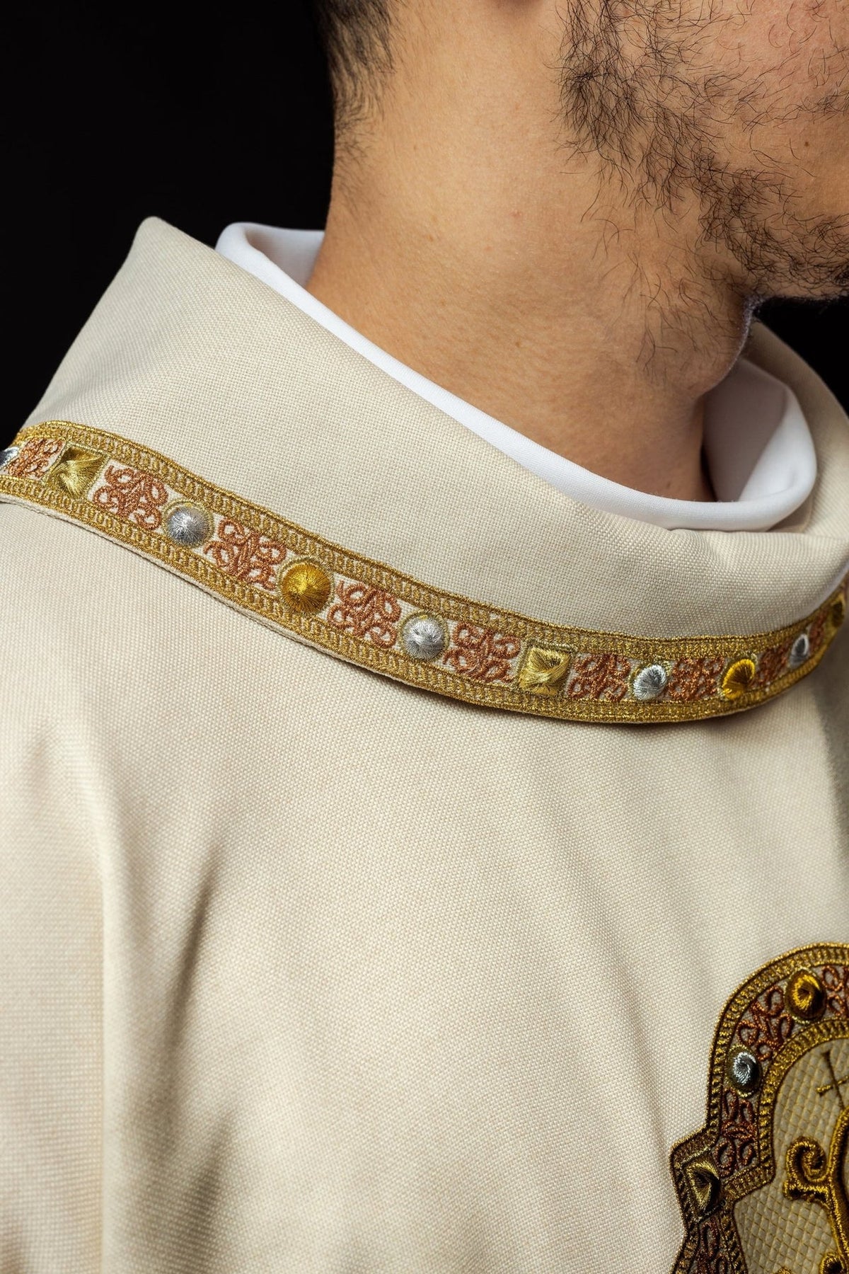 Ecru dalmatic close-up showing the ecru collar with embroidered gold and rose trim