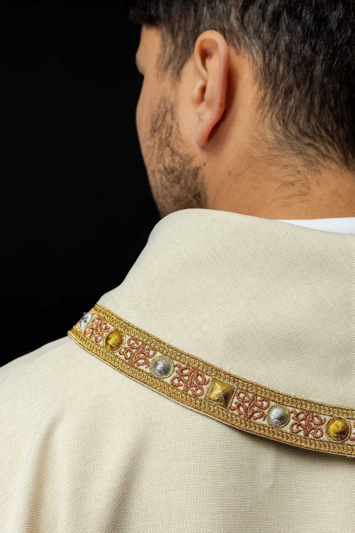 Ecru dalmatic side detail with embroidered collar trim and IHS motif edge