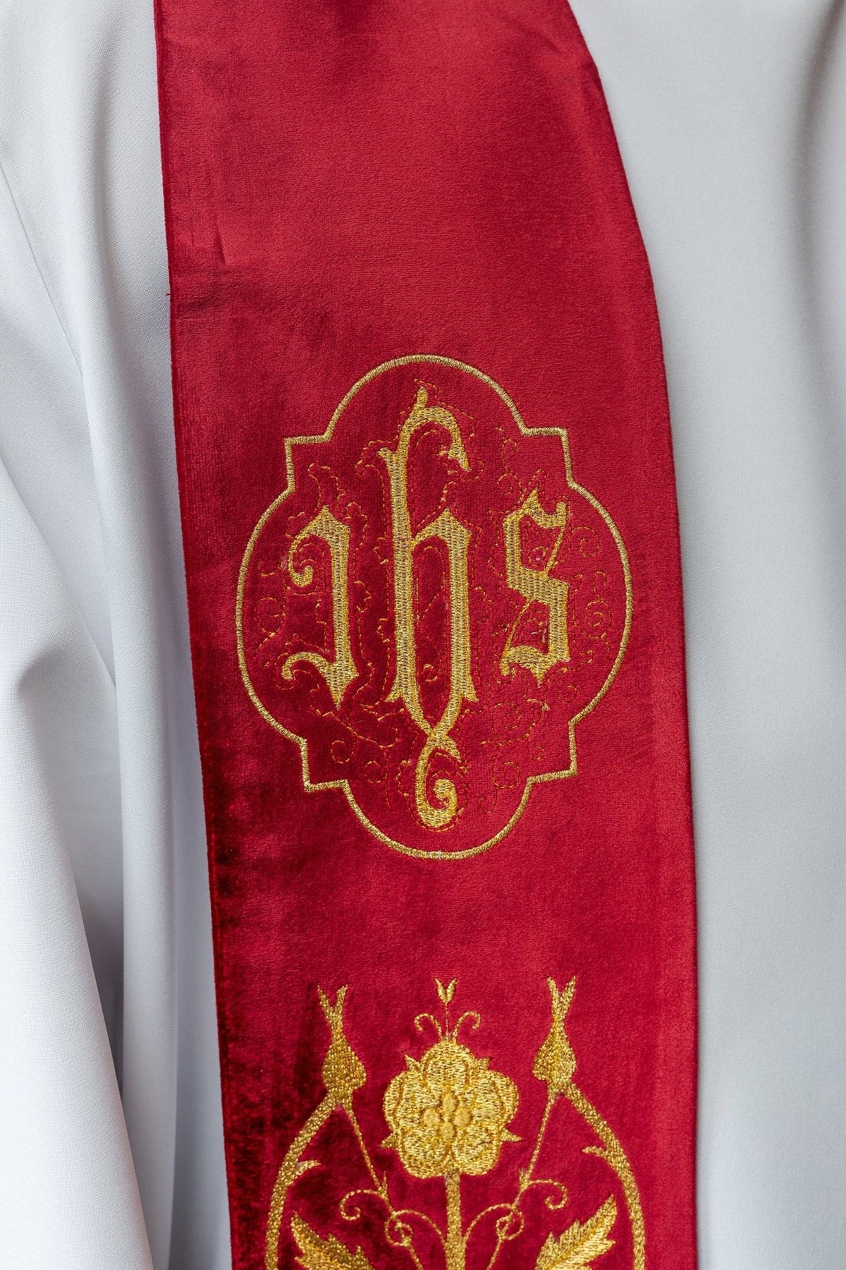 Red stole close-up showing embroidered gold IHS emblem