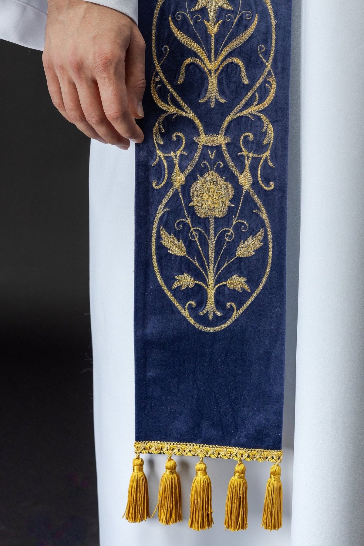 Purple stole close-up showing gold floral embroidery and tassel trim