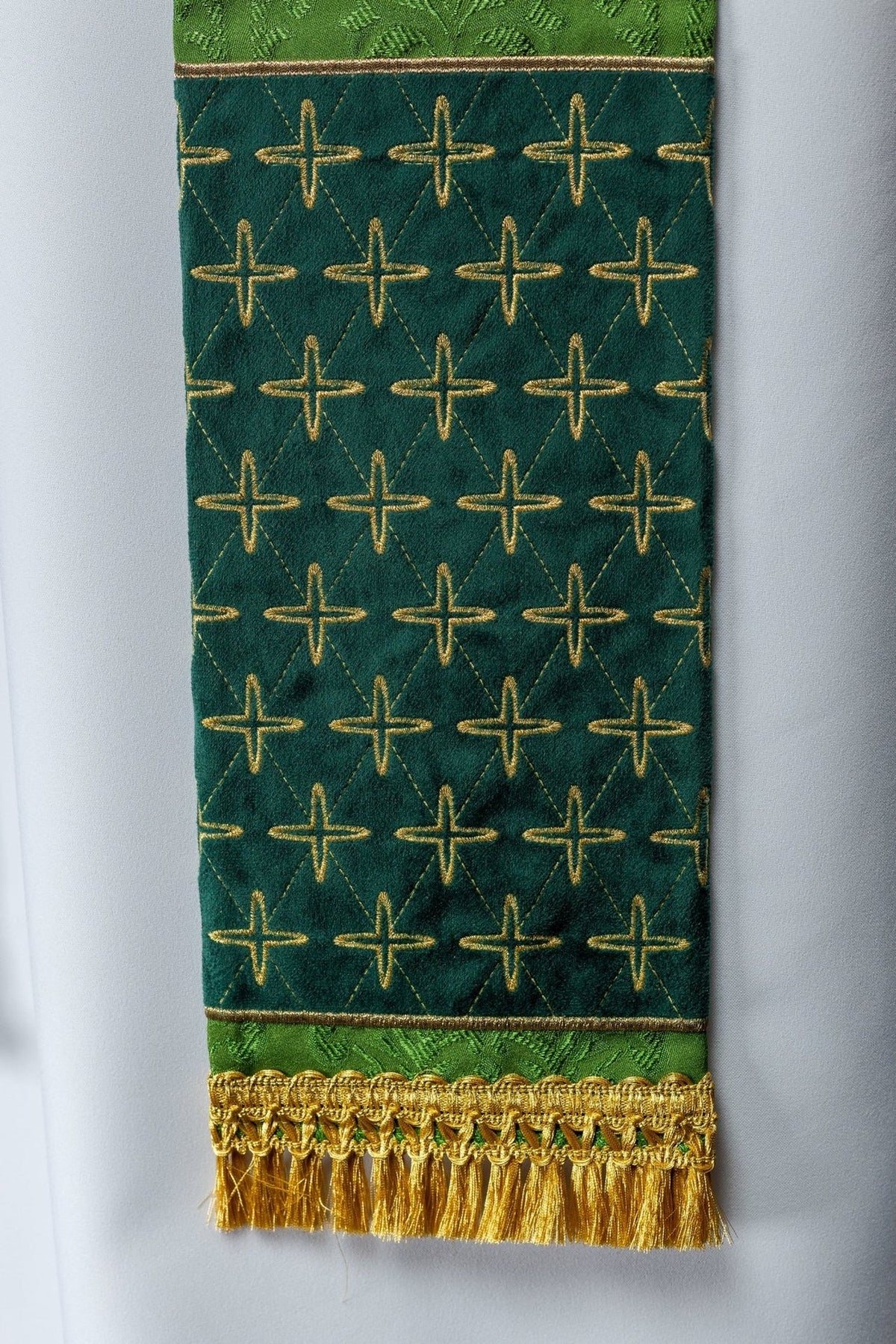 Green embroidered jacquard stole, close-up of repeated cross embroidery and gold fringe