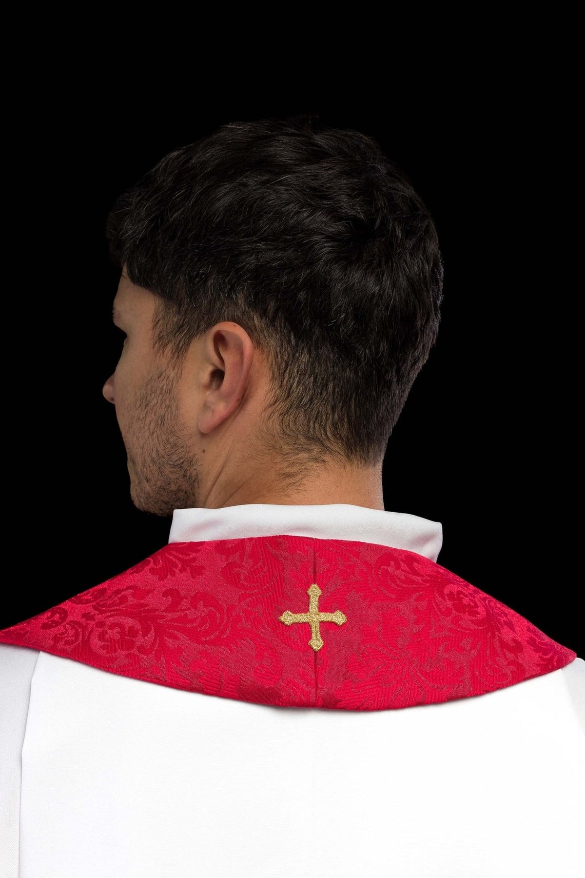 Red stole close-up showing repeated gold cross embroidery and decorative fringe