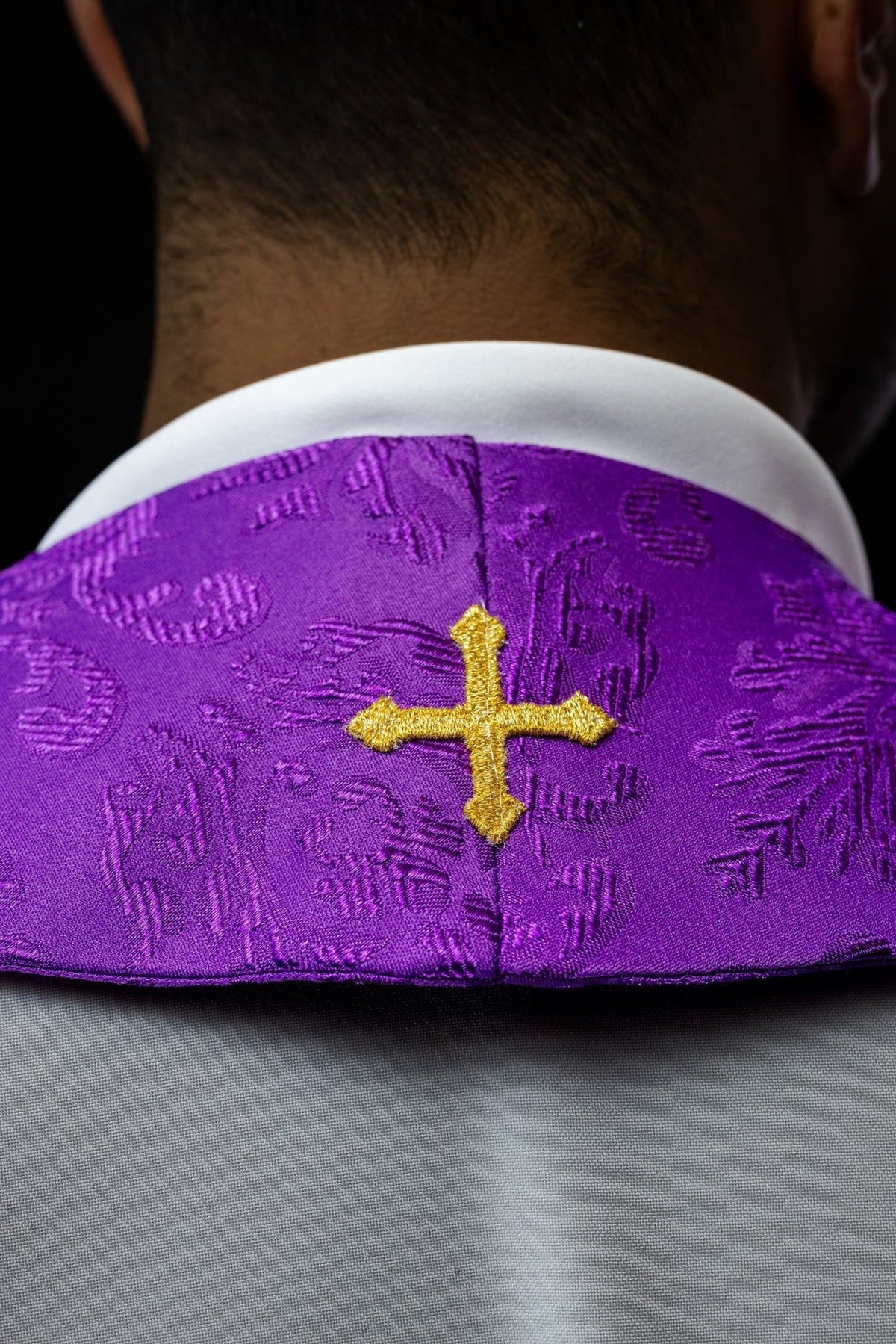 Purple stole close-up showing gold cross embroidery at the neckline