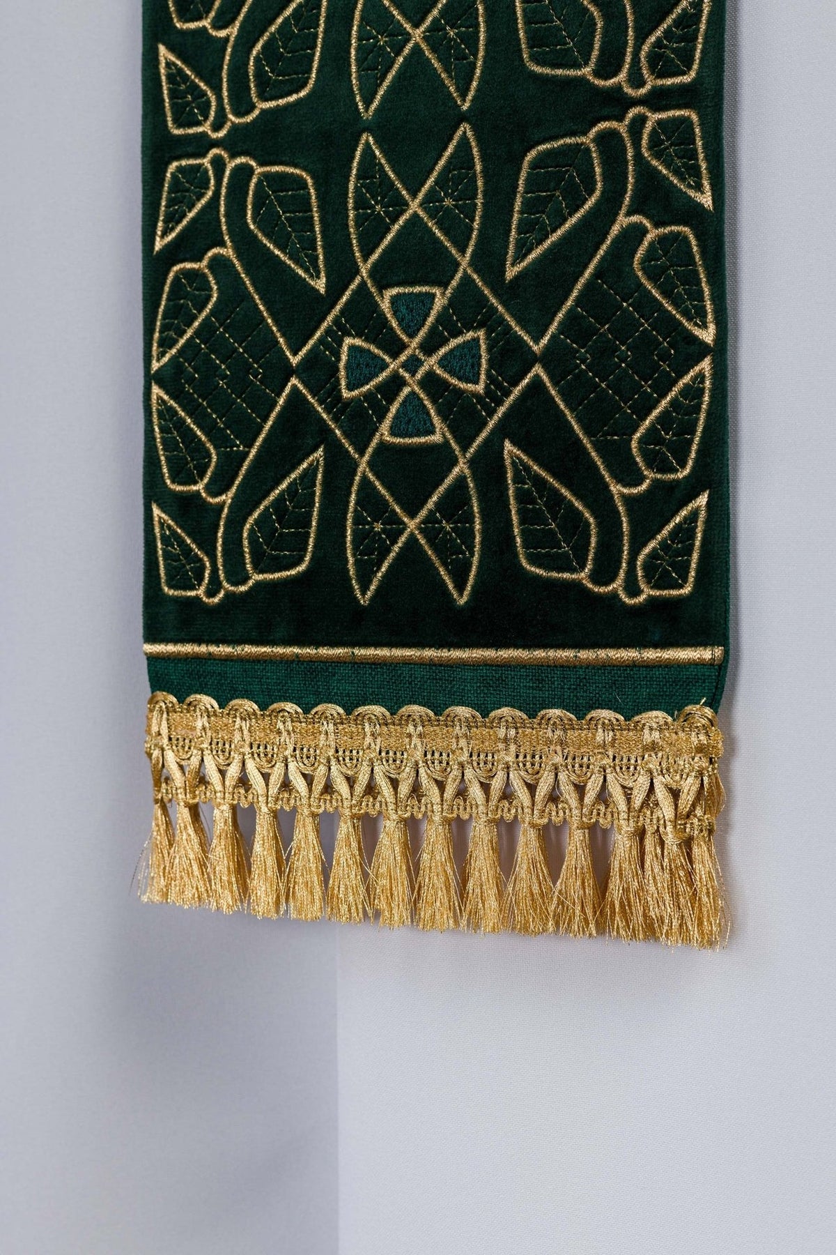 Green stole detail showing geometric embroidery, gold trim and fringe