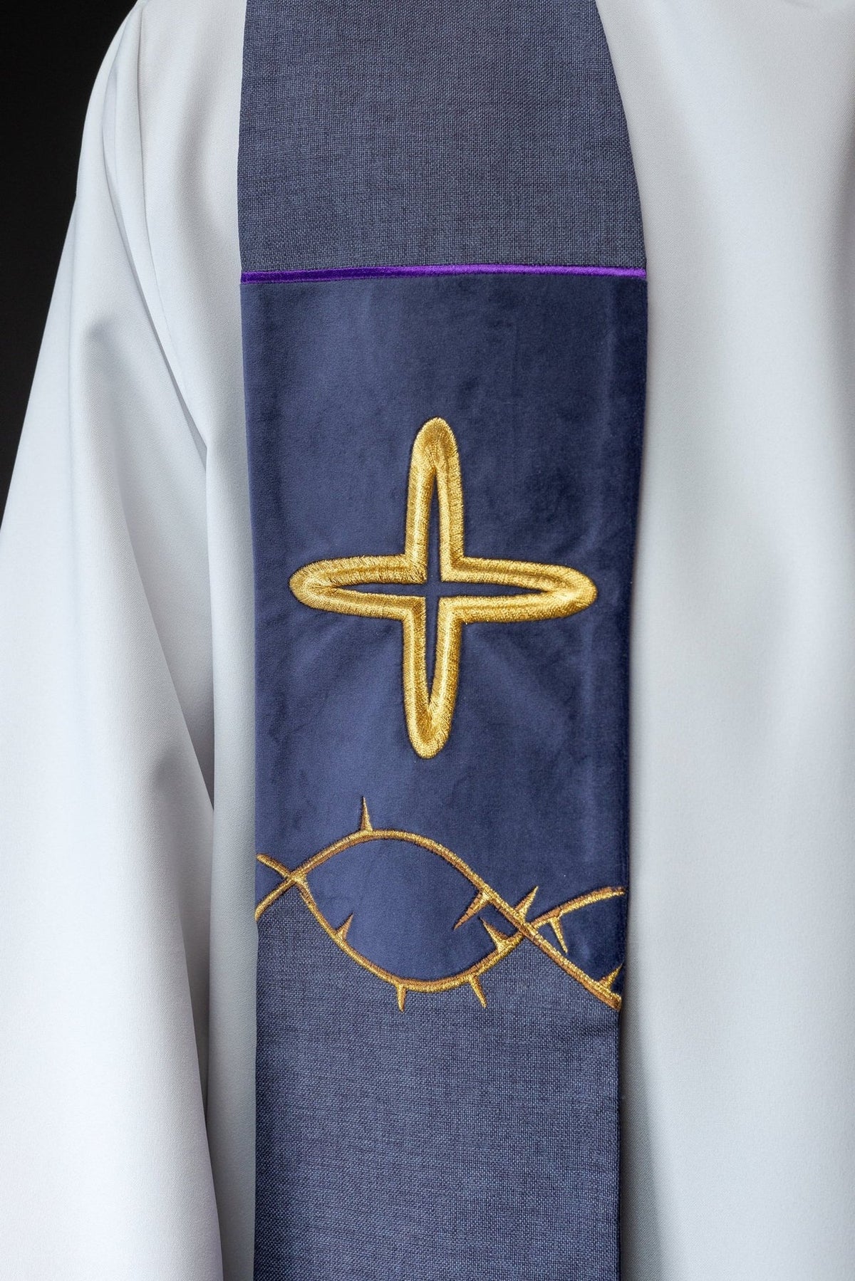 Purple stole close-up showing embroidered gold cross and thorn motif