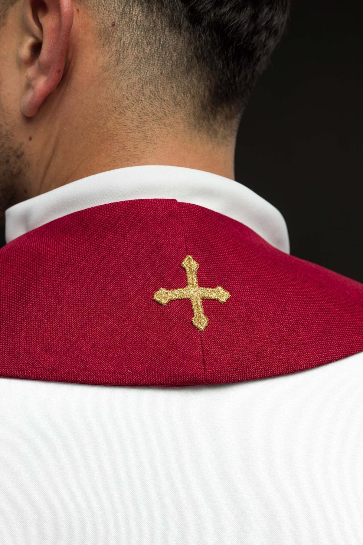 Red priest stole close-up showing gold embroidered cross at the neck