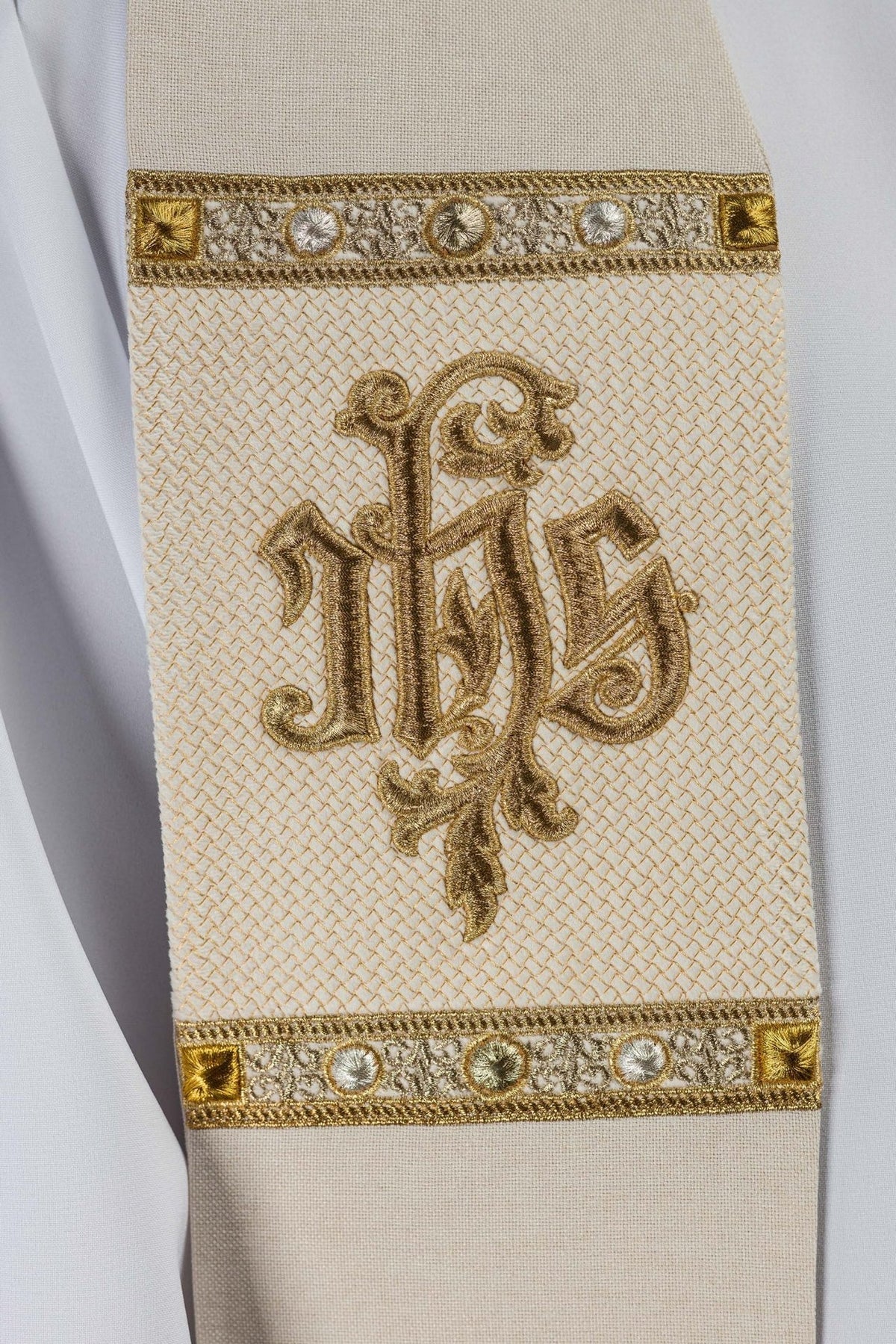 Ecru stole close-up showing gold IHS embroidery and patterned border