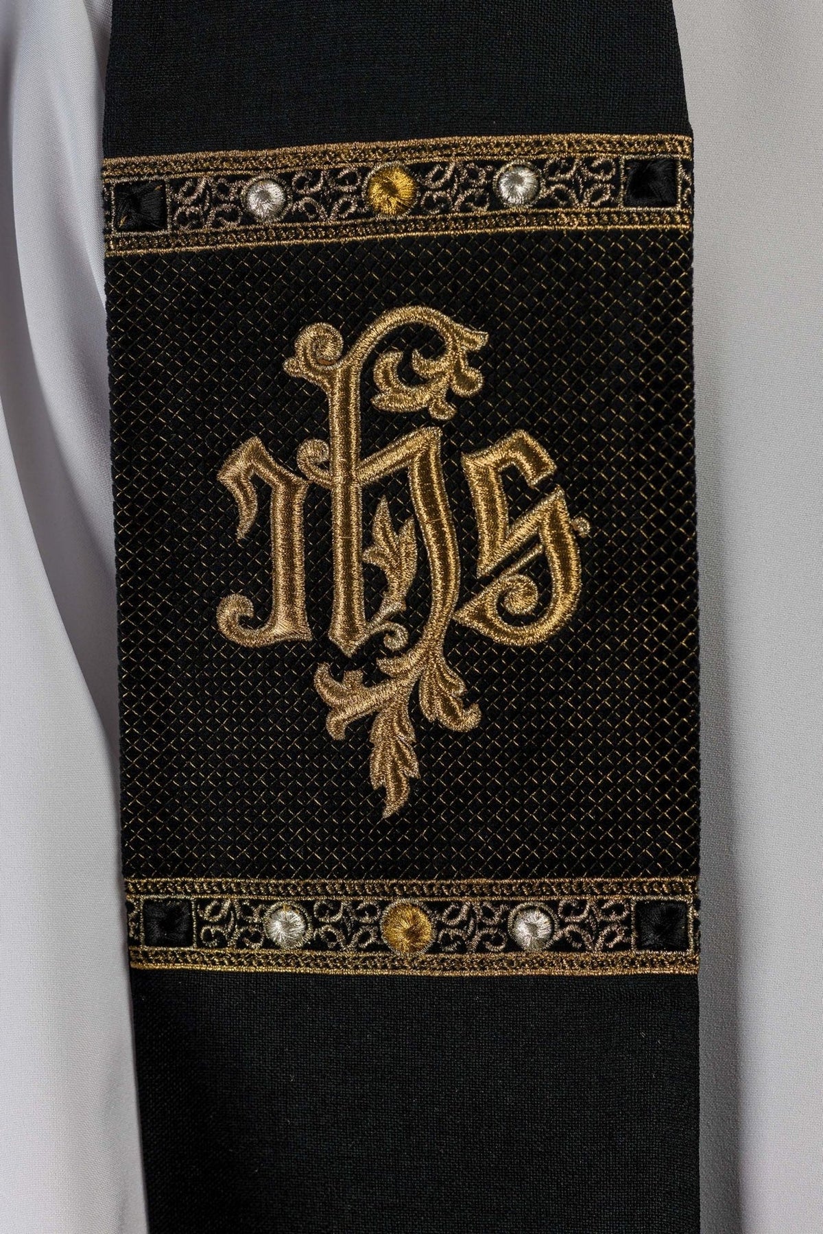 Black stole close-up showing gold embroidered IHS motif and patterned bands