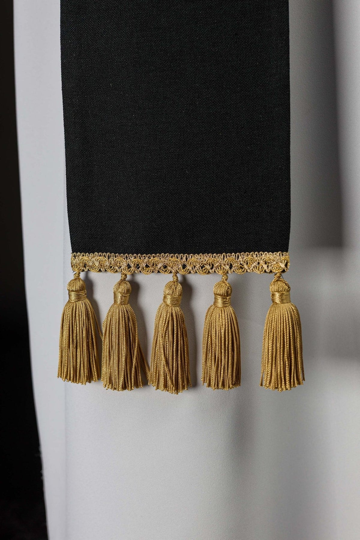 Black stole close-up showing gold trim and hanging tassels