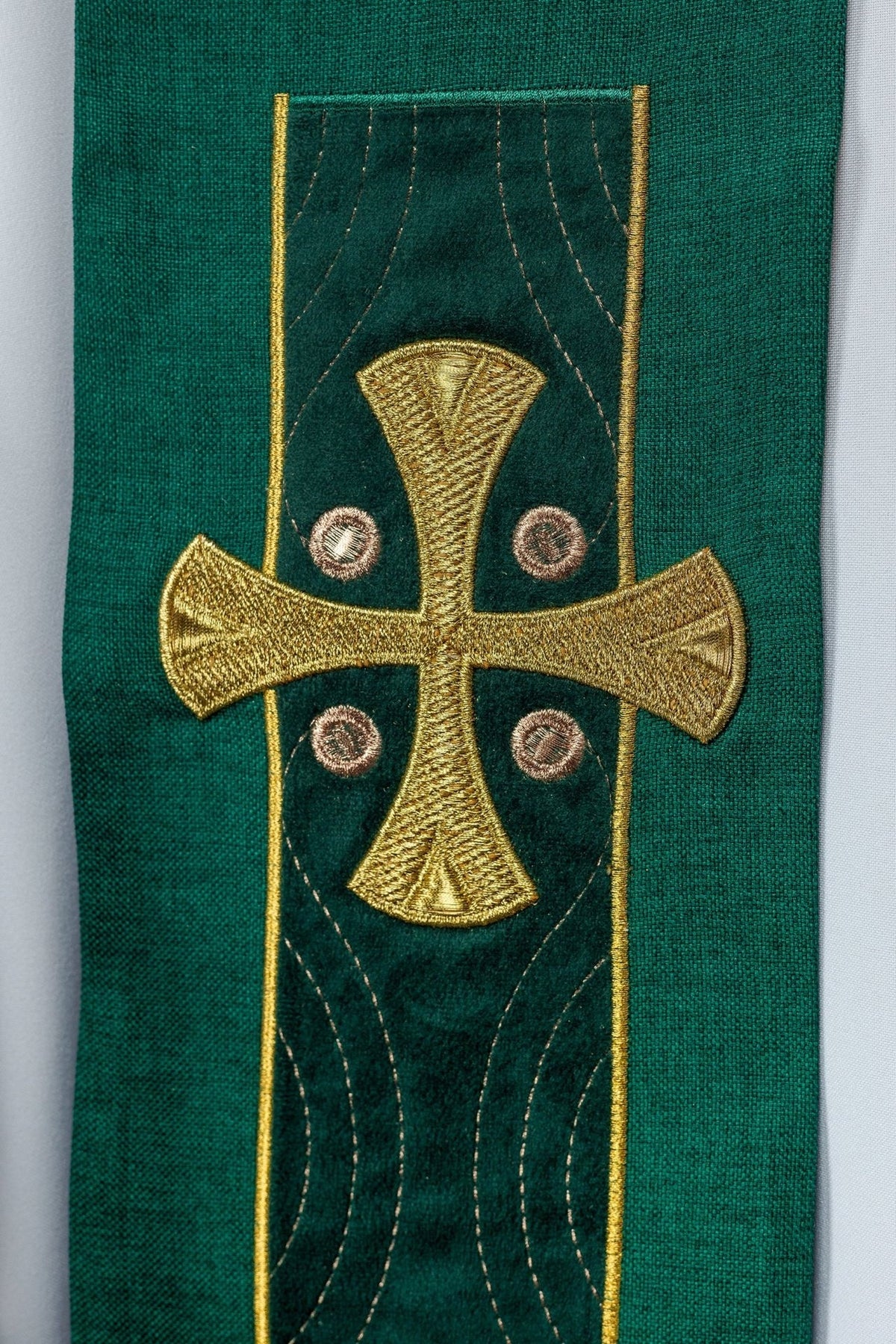 Green stole close-up showing embroidered gold cross with decorative stitching