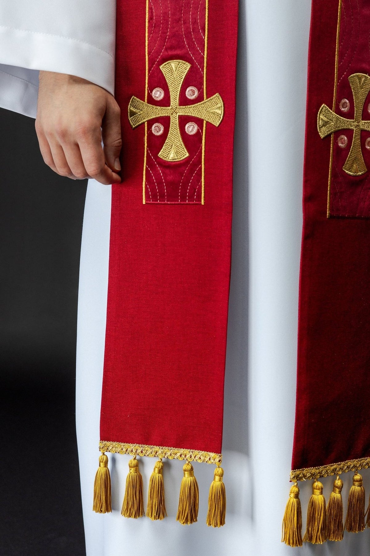 Red stole close-up showing a gold cross, embroidery, border and tassels