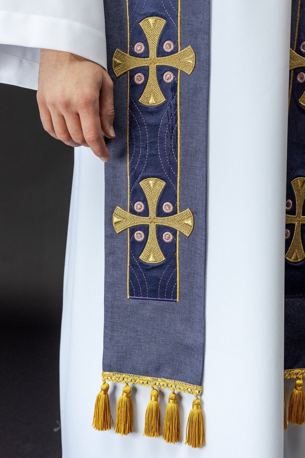 Purple stole detail showing repeated gold cross embroidery and gold tassel edging