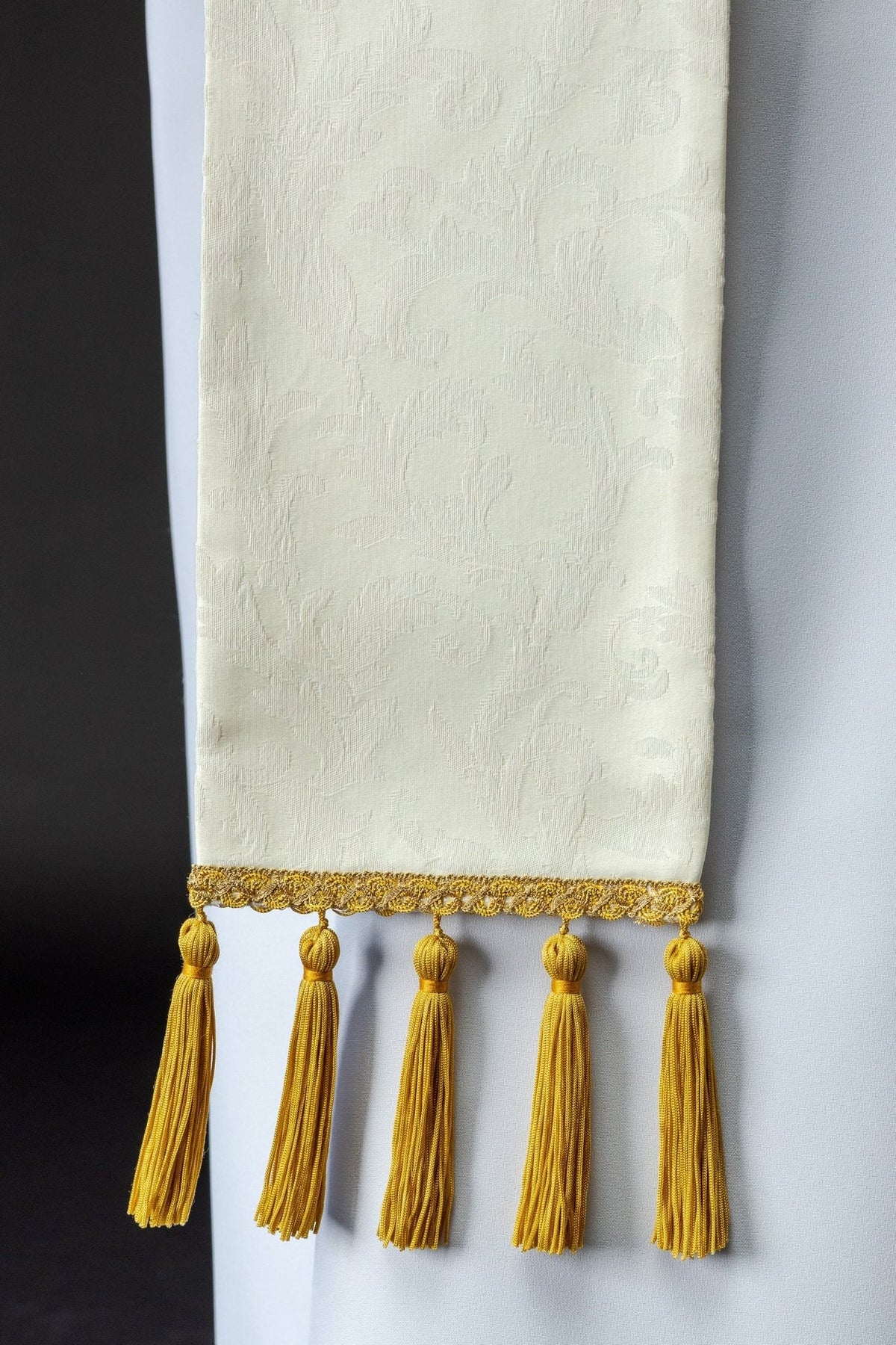 Ecru jacquard stole detail with gold tassels and decorative trim