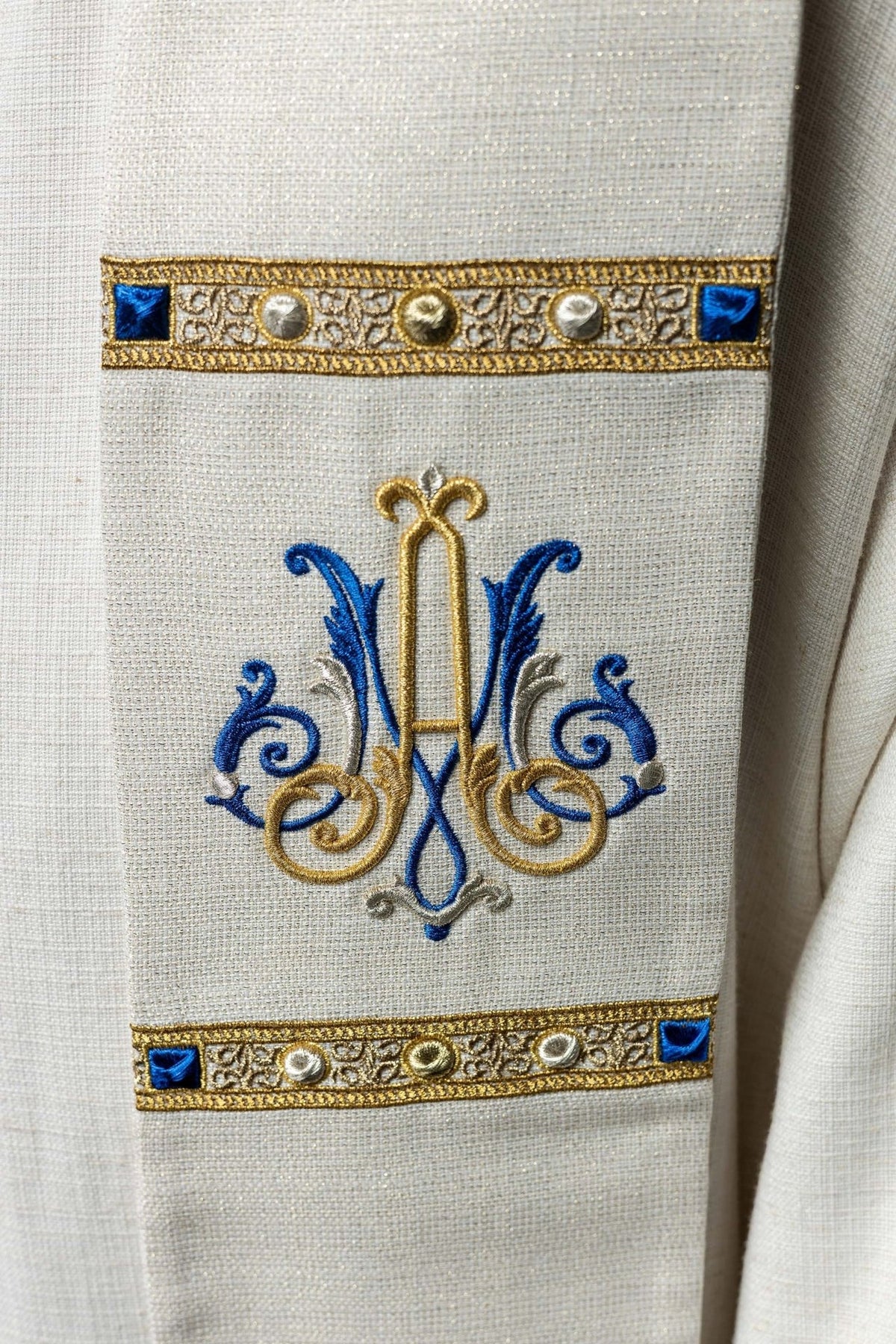 Ecru stole close-up showing embroidered gold and blue Marian symbol