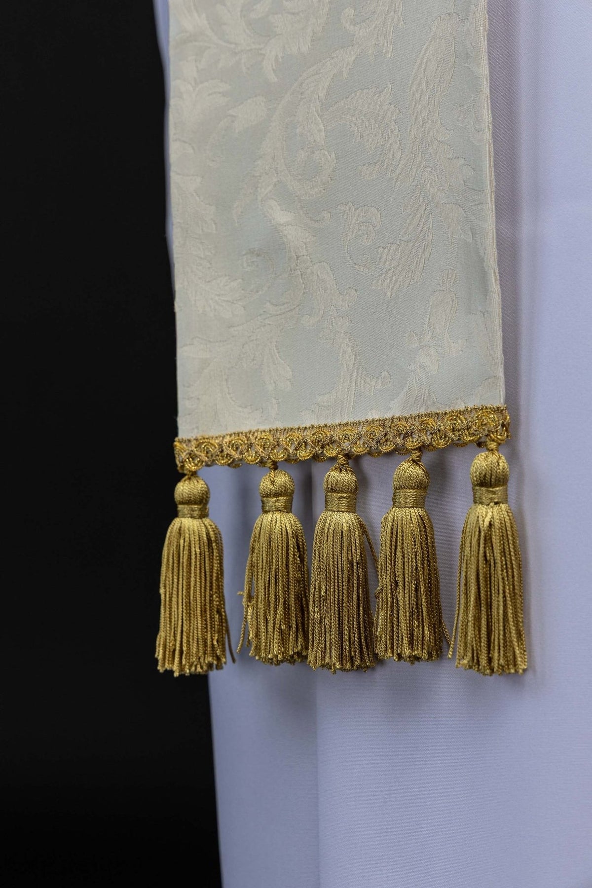 Holy Family stole close-up showing ecru jacquard fabric, gold trim and tasselled end