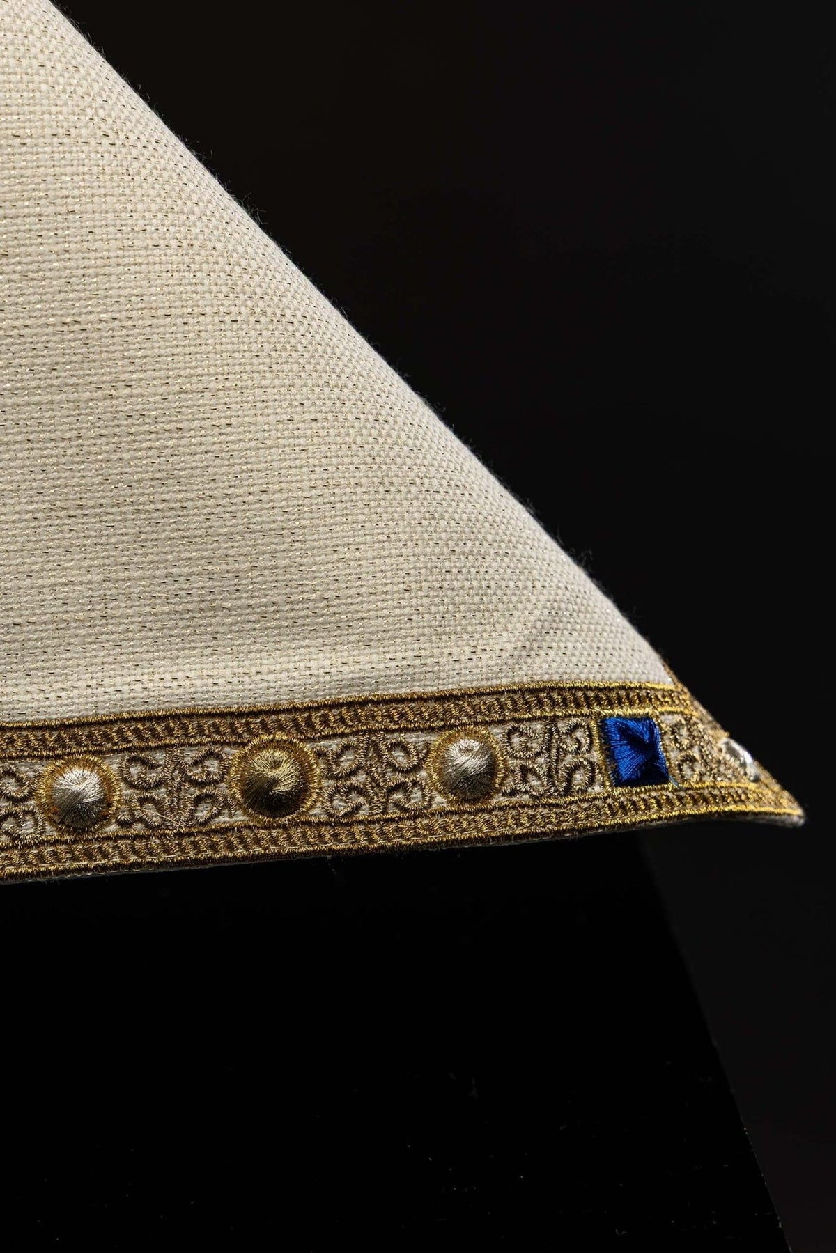 Chalice veil detail showing ecru fabric and gold border with blue accents