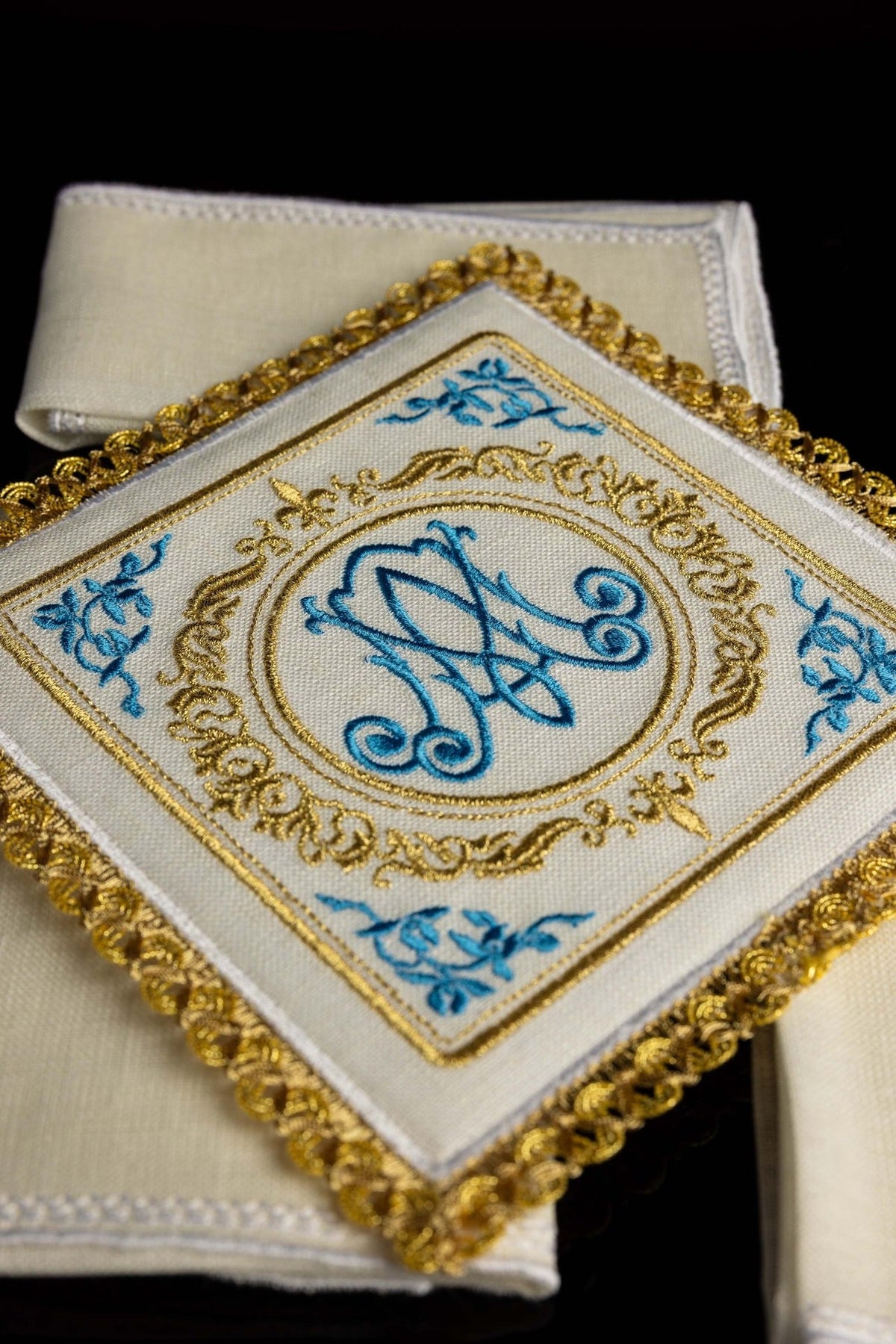 Altar linen set close-up showing blue Marian motif embroidery framed by gold trim