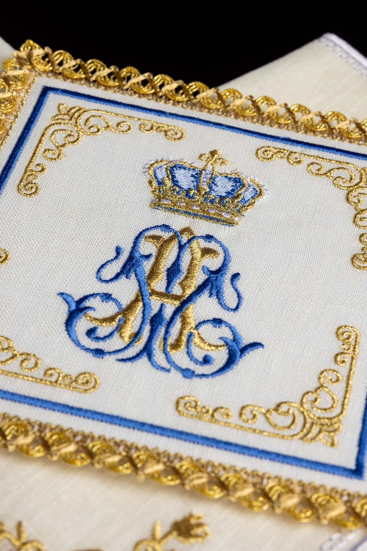 Altar linen set close-up showing crowned blue and gold Marian monogram embroidery