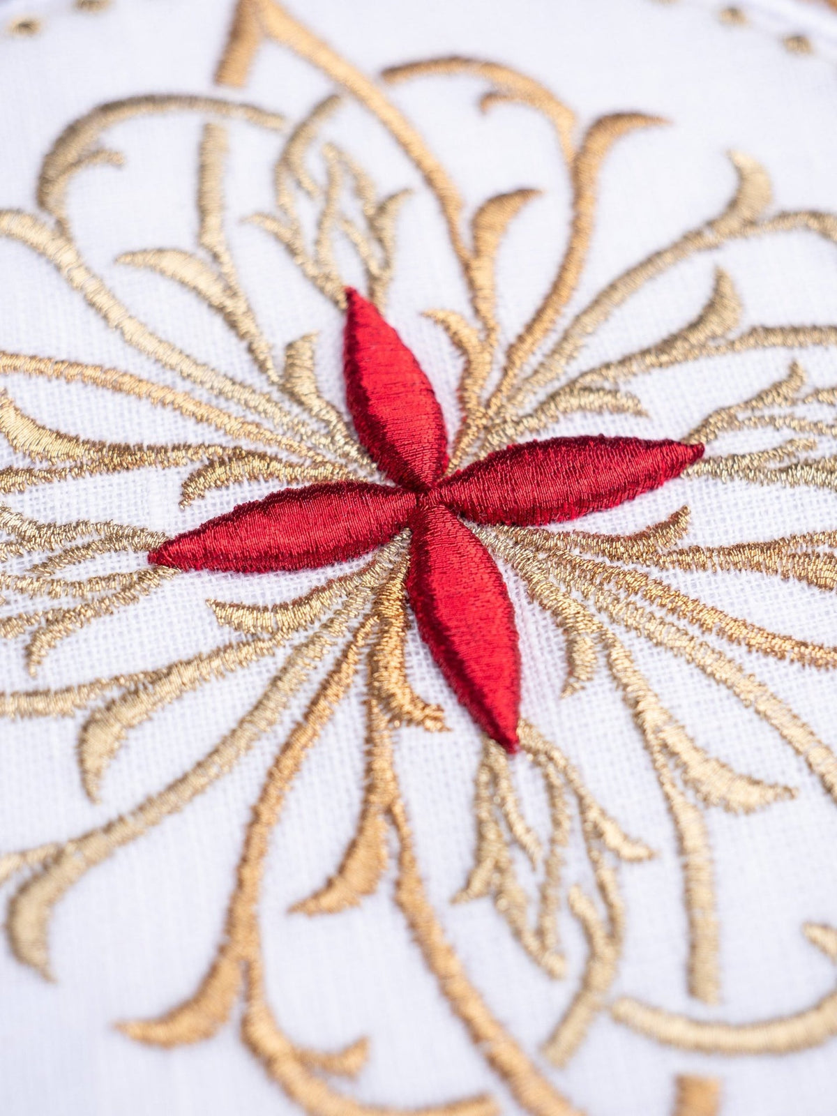 Round chalice pall close-up with red embroidered cross and gold floral embroidery