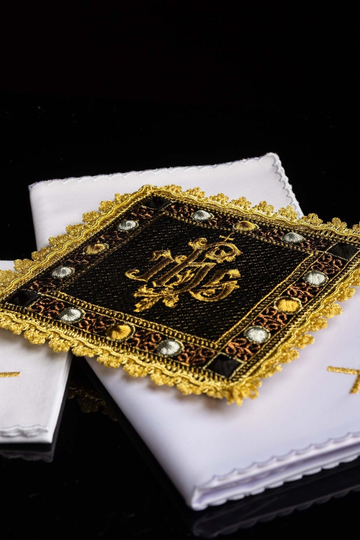 Altar linen set close-up showing black velvet chalice pall with gold embroidered IHS and ornate trim