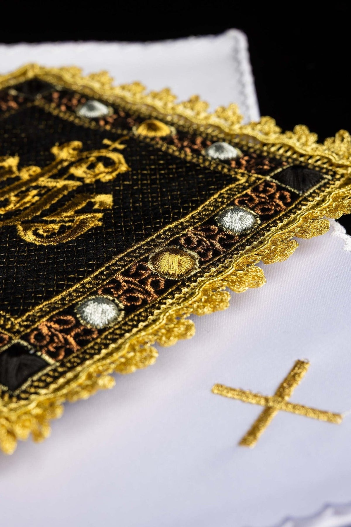 Black velvet chalice pall and white altar linen detail with gold embroidered cross