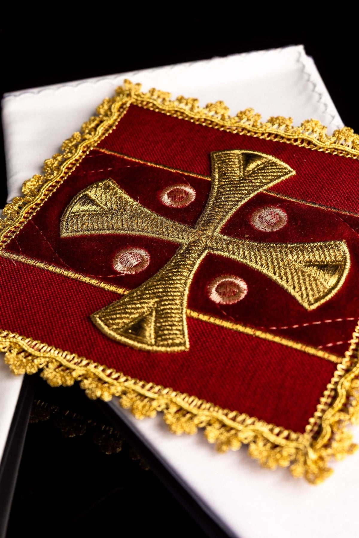 Red corporal close-up showing gold cross embroidery and ornate gold trim