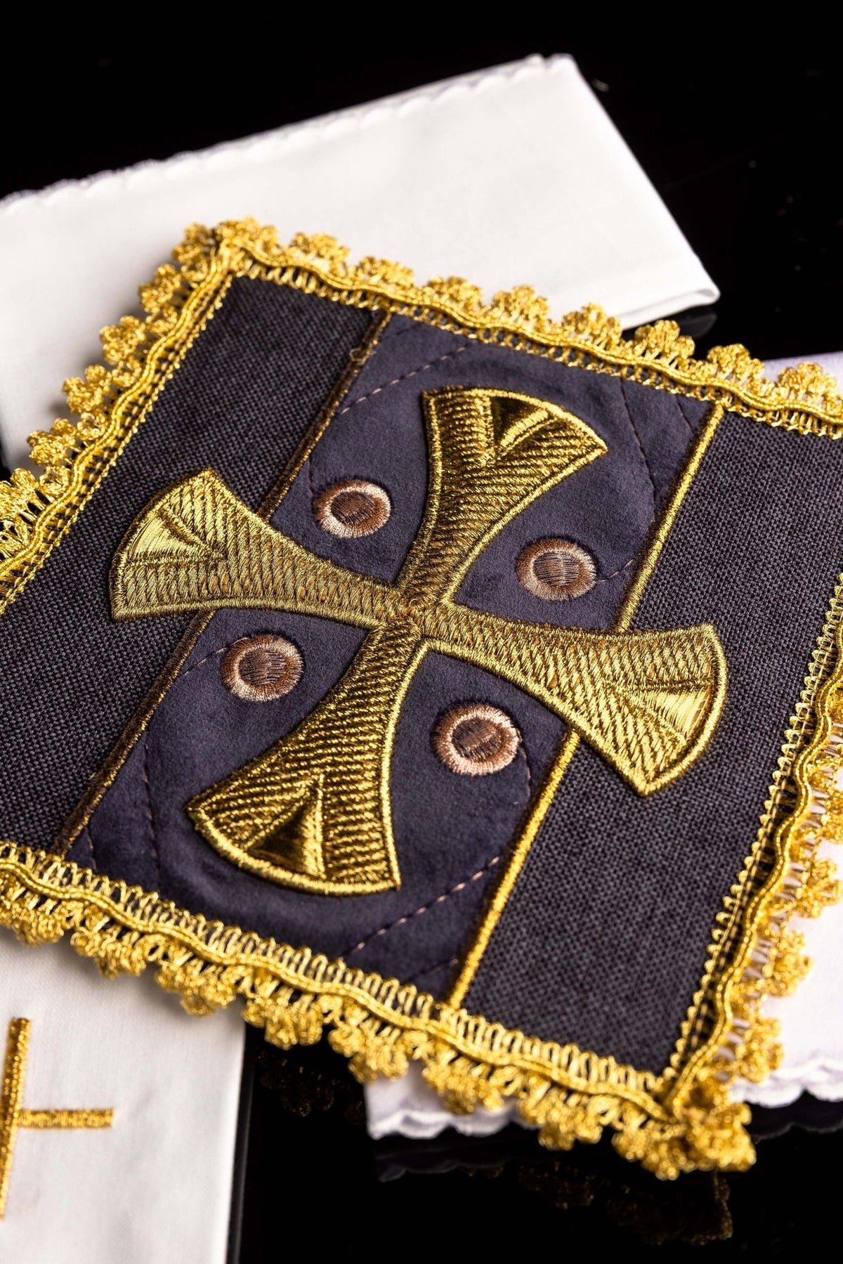 Altar linen set close-up showing purple velvet chalice pall with gold cross embroidery and ornate gold trim