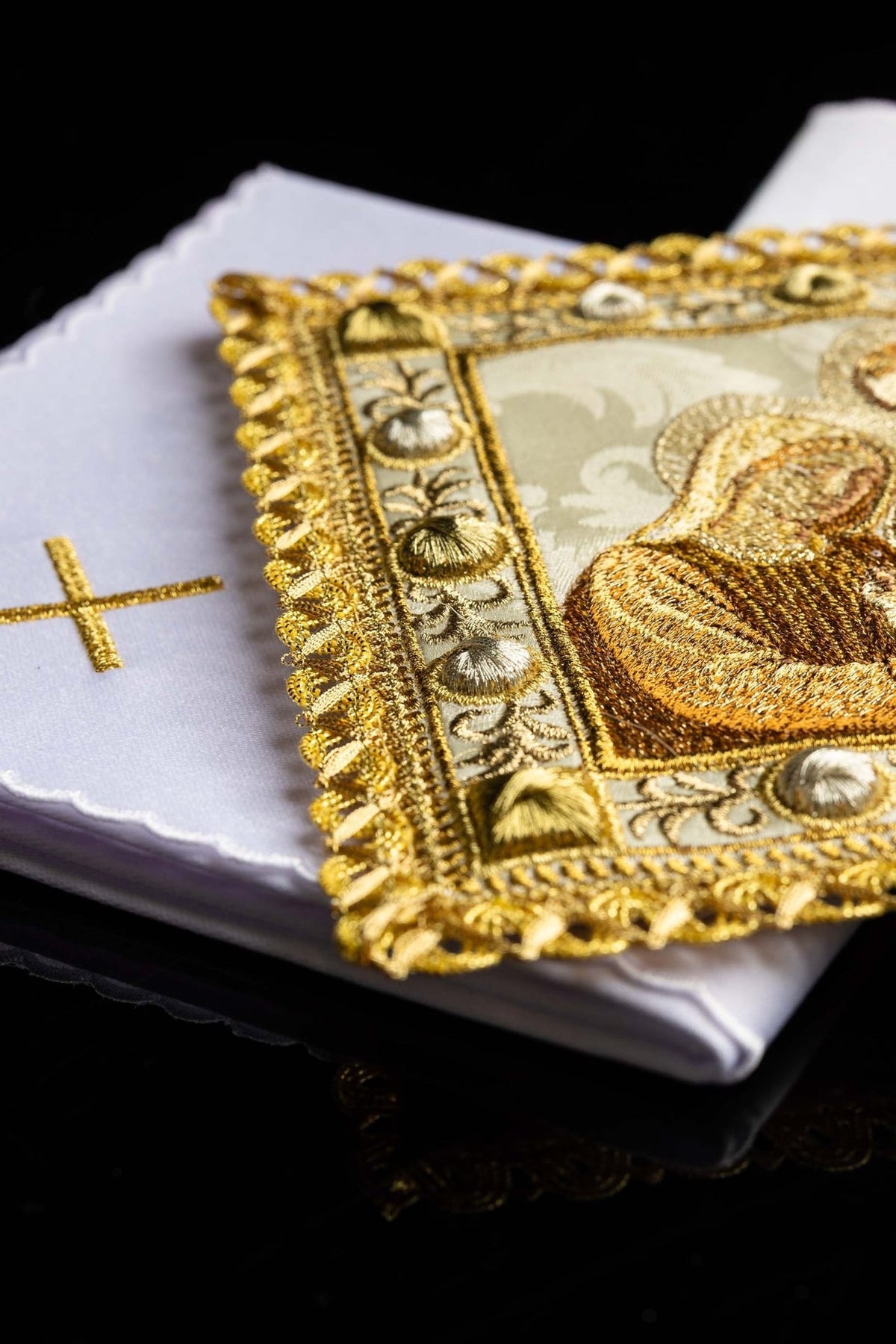 Altar linen set folded beneath an embroidered Holy Family panel with gold trim