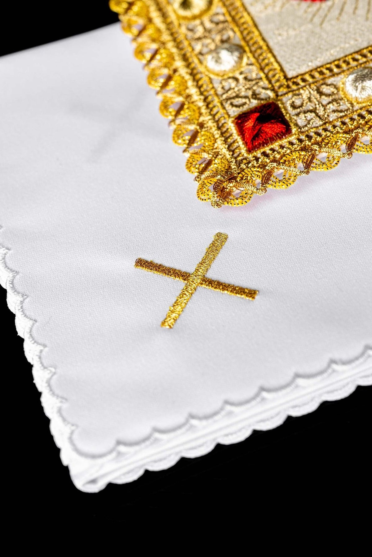 Altar linen set close-up showing a white cloth with a gold embroidered cross and scalloped edge