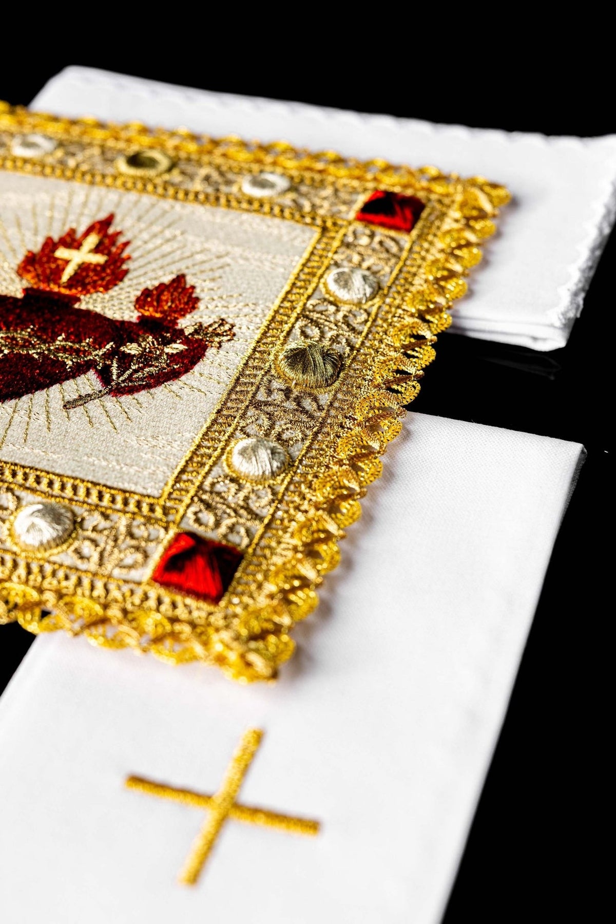 Altar linen set detail showing gold border embroidery, red corner accents and white cloths