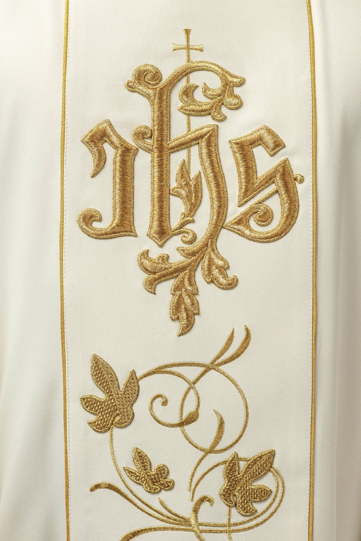 Ecru chasuble close-up showing gold IHS embroidery and floral orphrey