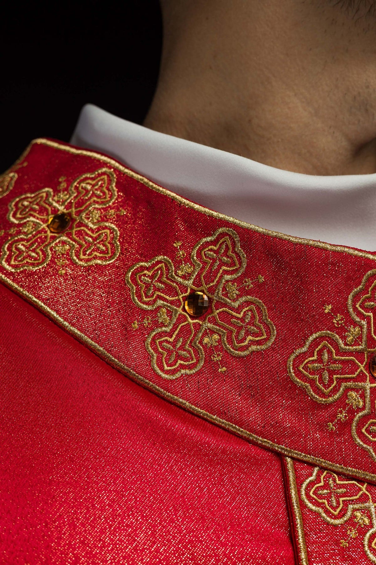 Red chasuble close-up of gold cross embroidery with stone-set centers