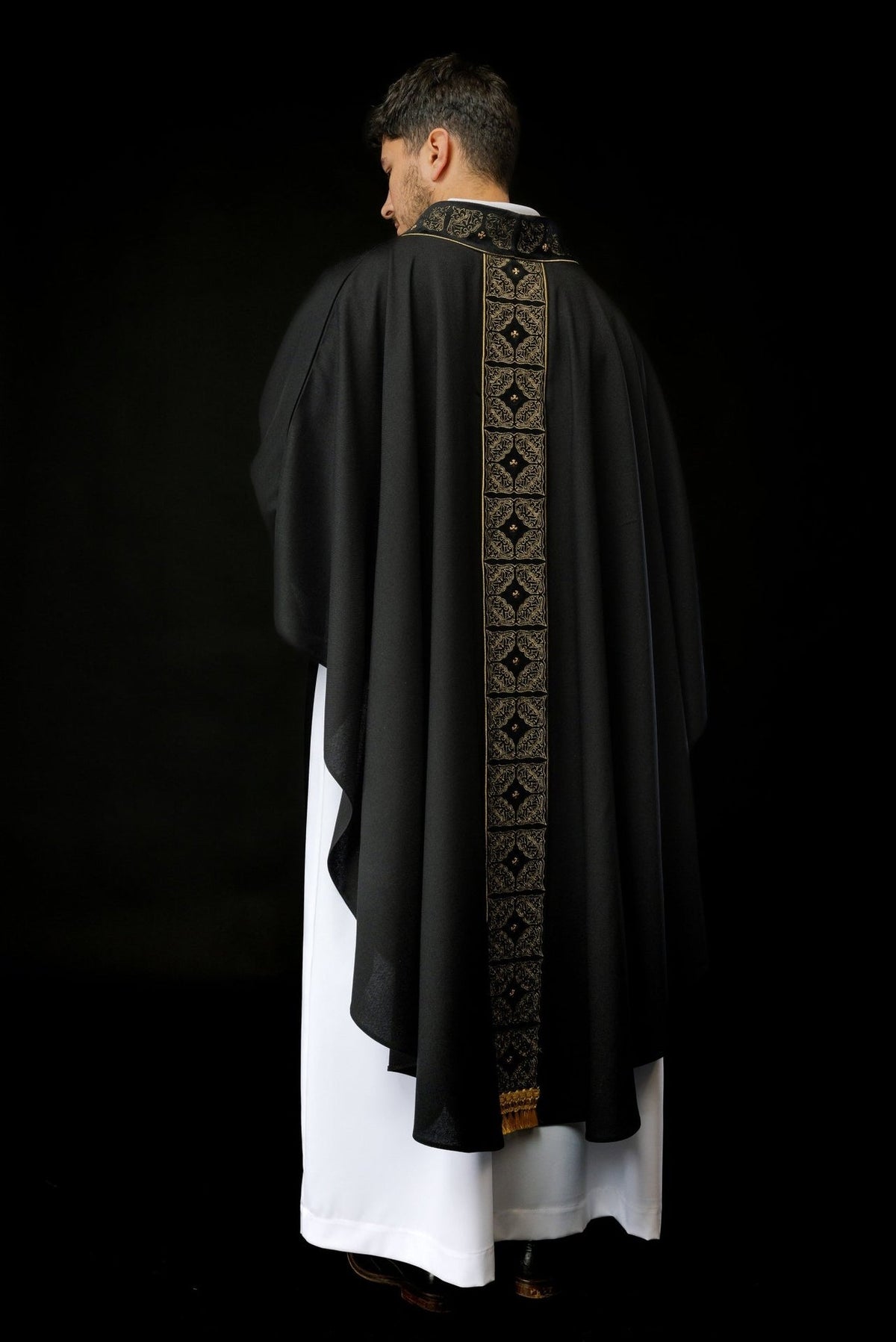 Black chasuble back worn view with embroidered orphrey and gold fringe