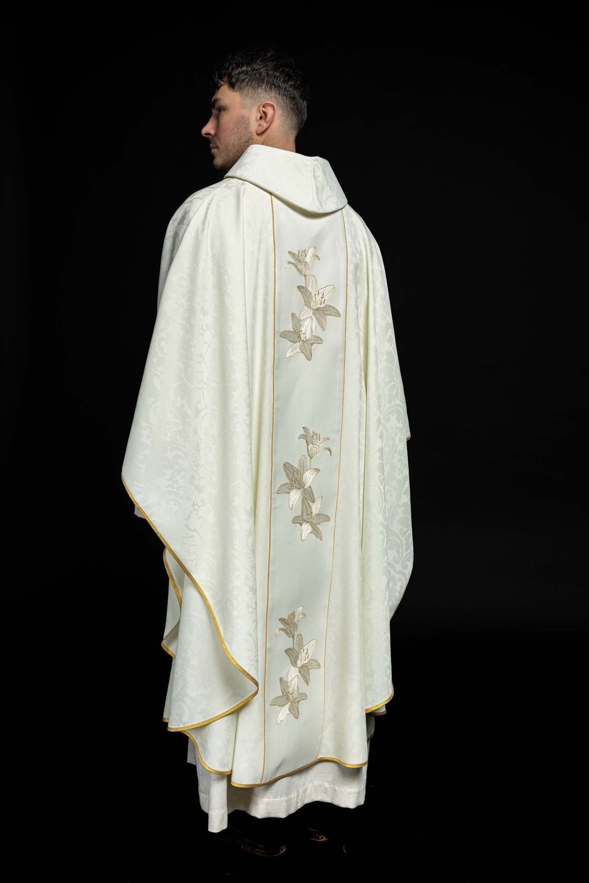 Chasuble back three-quarter view with embroidered lily panels and gold-trimmed edges
