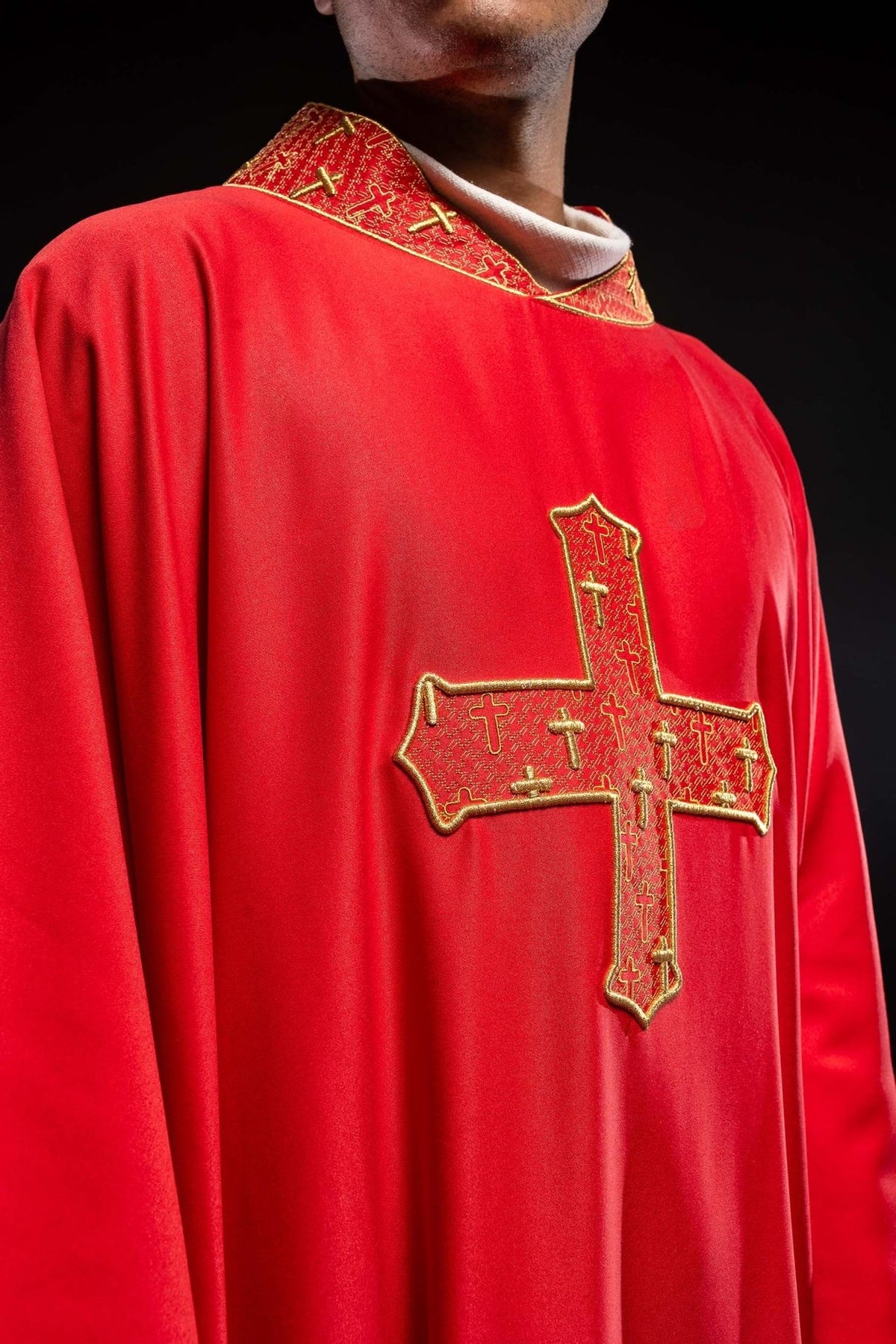 Red chasuble close-up showing embroidered cross and patterned collar
