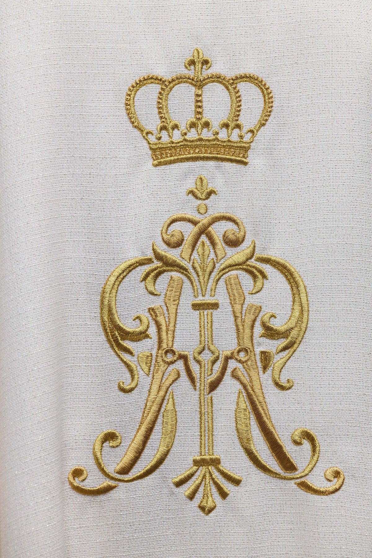 Liturgical chasuble close-up of embroidered gold Marian monogram and crown