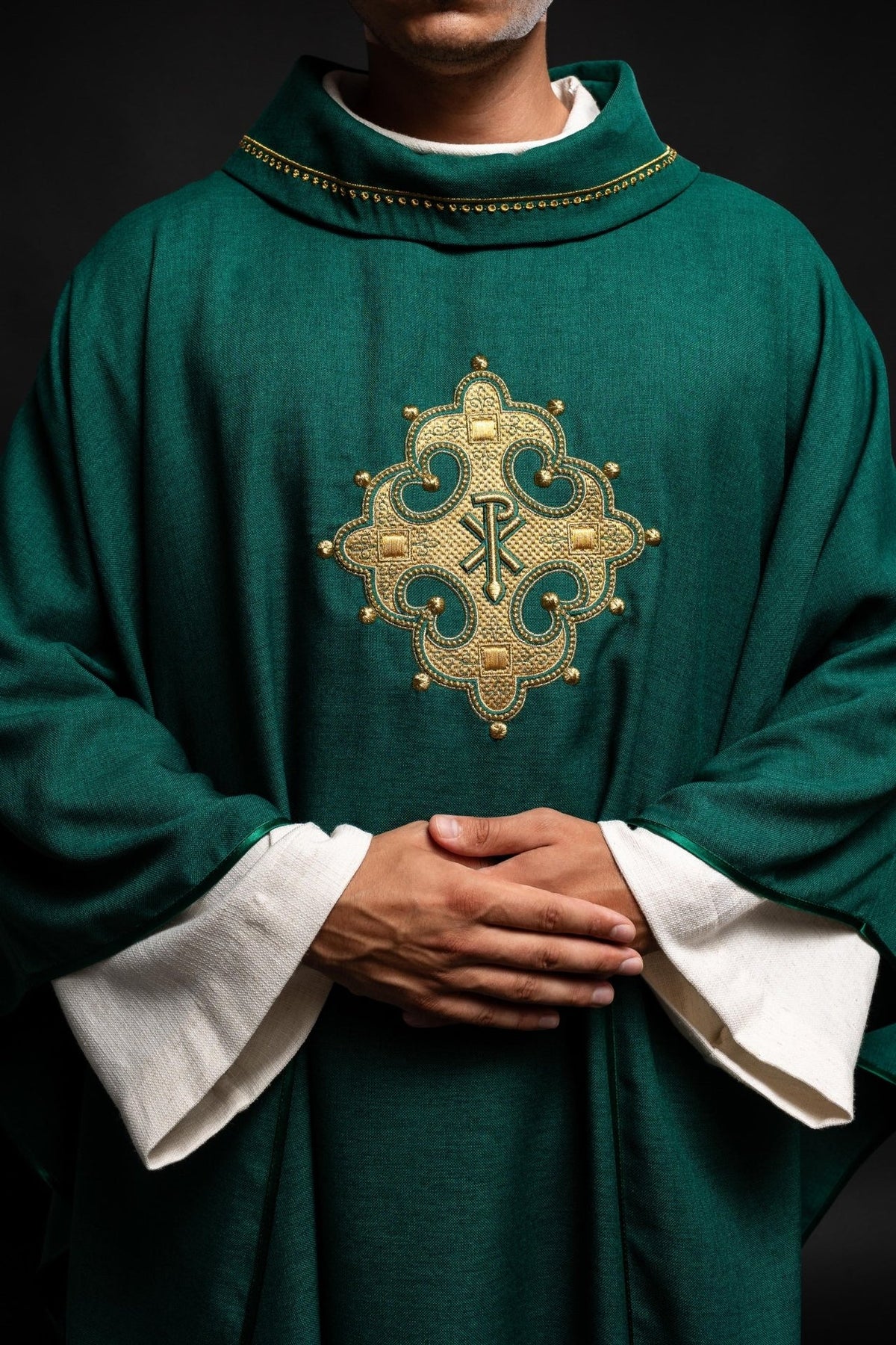 Green chasuble close-up showing embroidered cross and gold collar trim