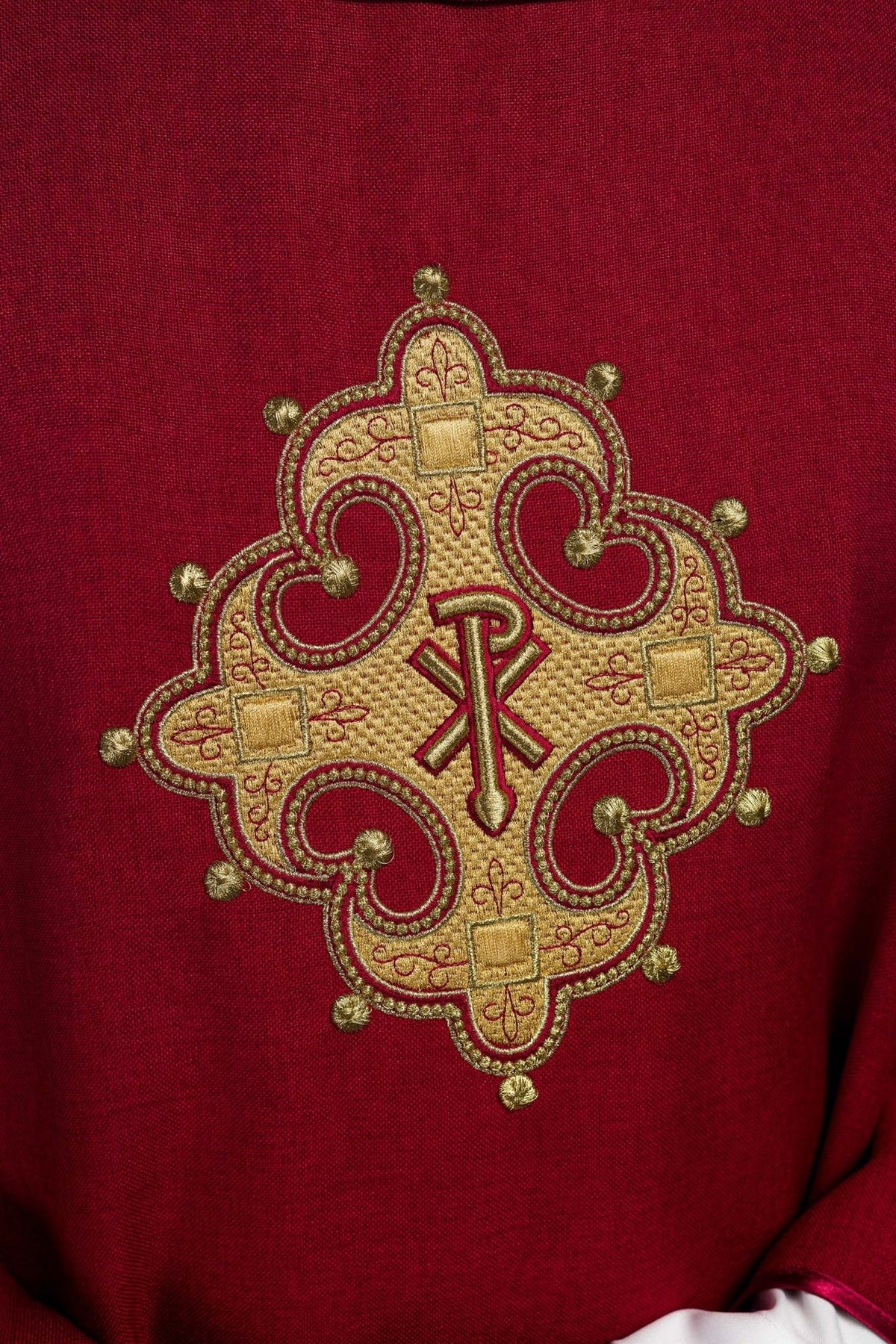 Red chasuble close-up showing embroidered gold cross