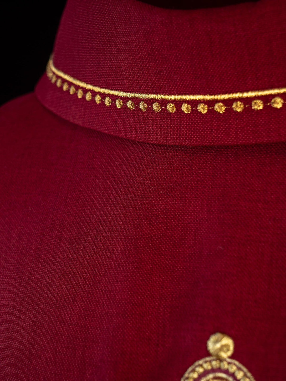 Red chasuble close-up showing gold embroidered collar trim