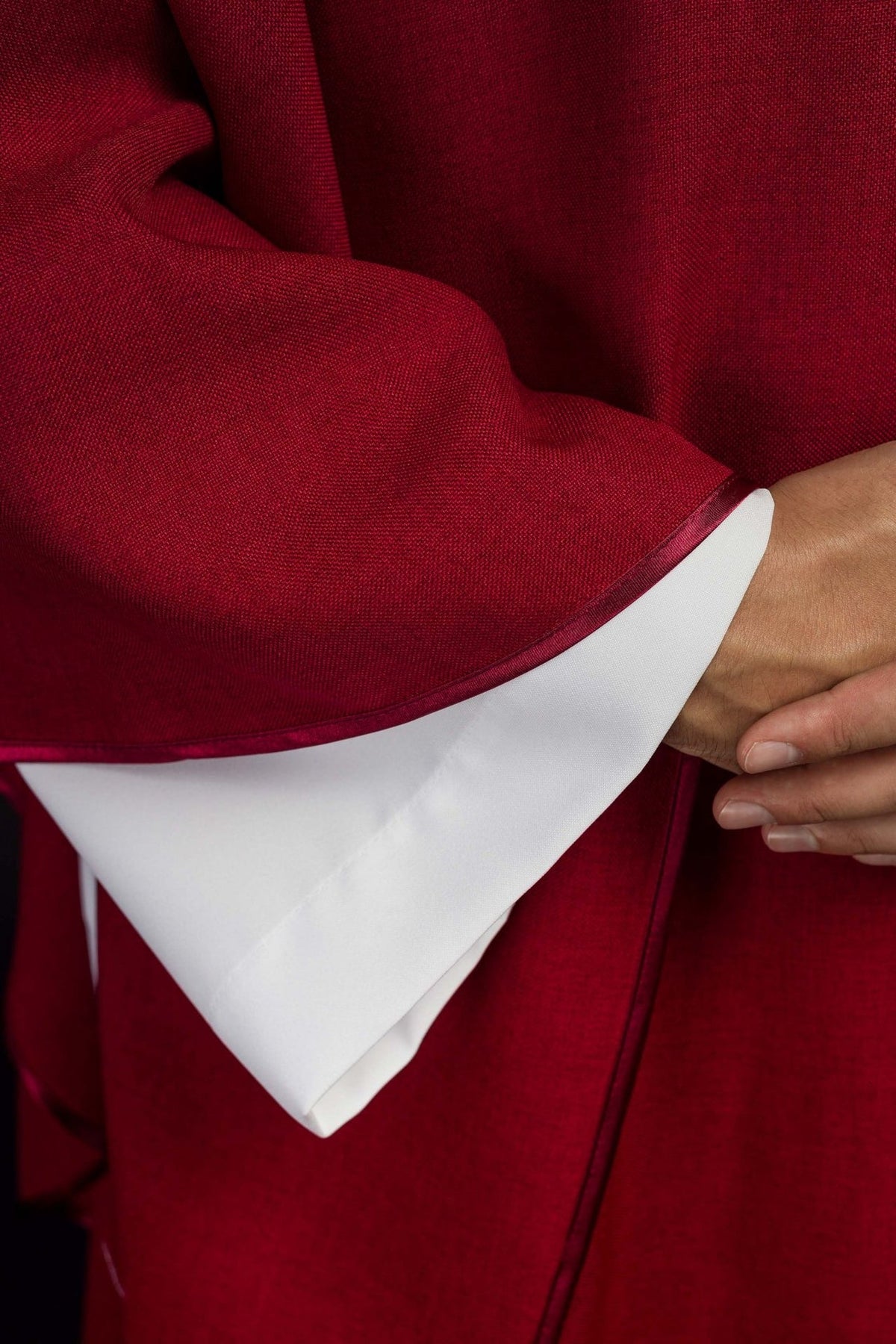 Red chasuble close-up showing fabric and finished sleeve trim