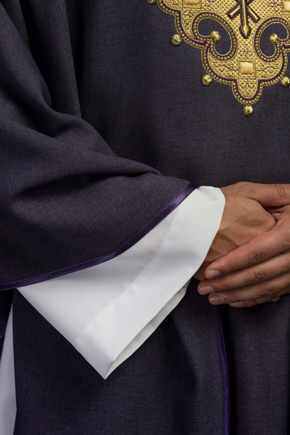 Purple chasuble close-up showing sleeve trim and white cuff