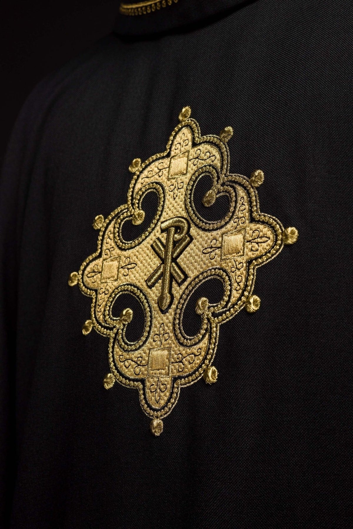 Black chasuble close-up of ornate gold embroidered cross