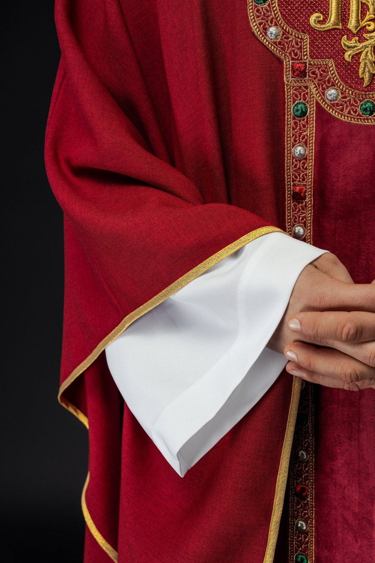 Red chasuble side close-up showing sleeve and gold trim